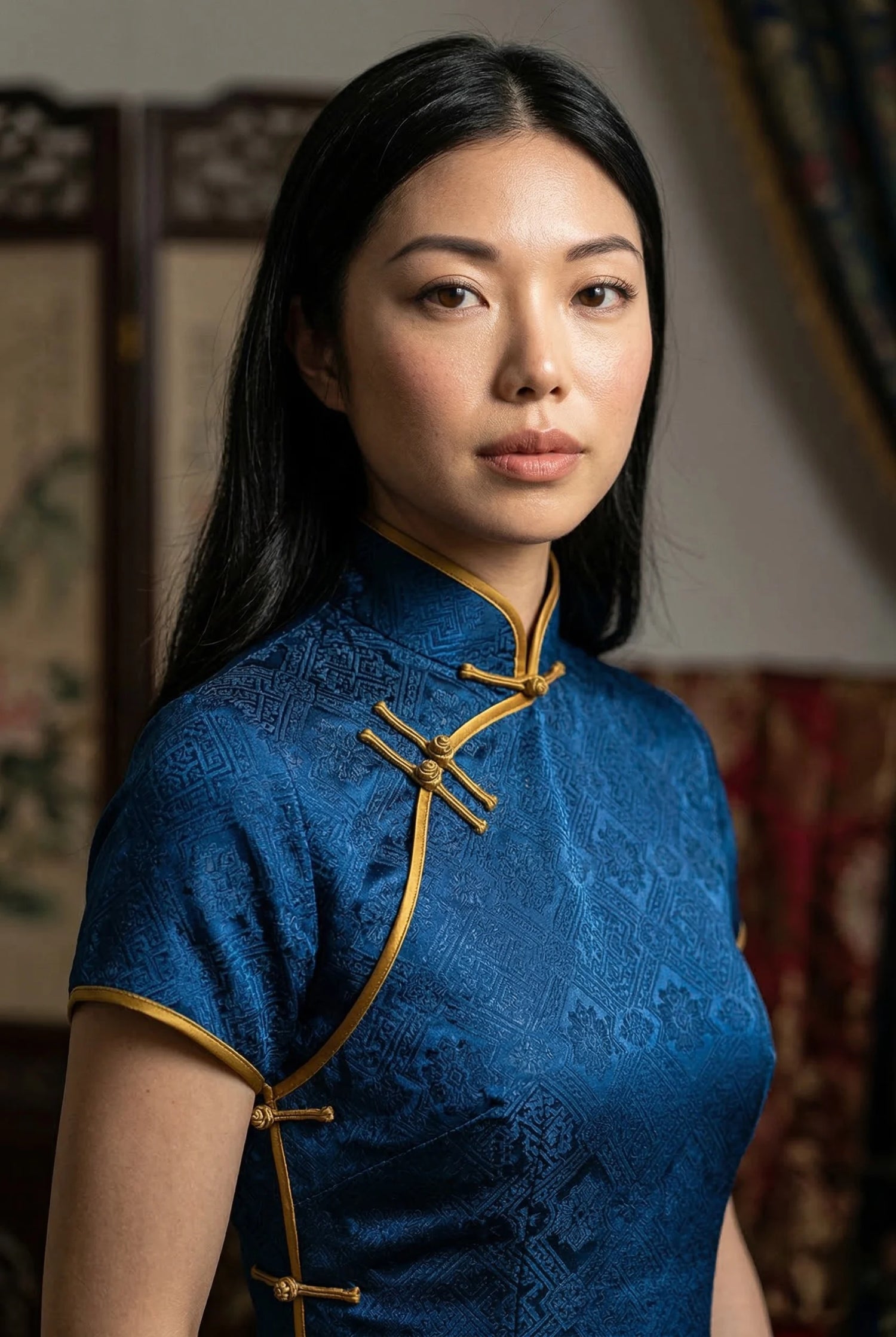 Close-up of a vintage 1930s style blue brocade qipao by Maison Hua, showcasing gold hand-finished Pankou buttons and bias-cut piping for structural alignment