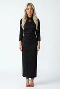Front full view of a woman in a long black brocade qipao.