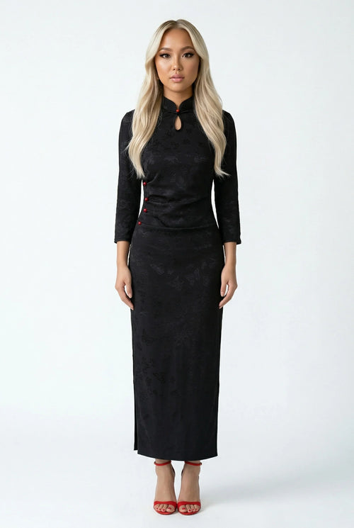 Front full view of a woman in a long black brocade qipao.