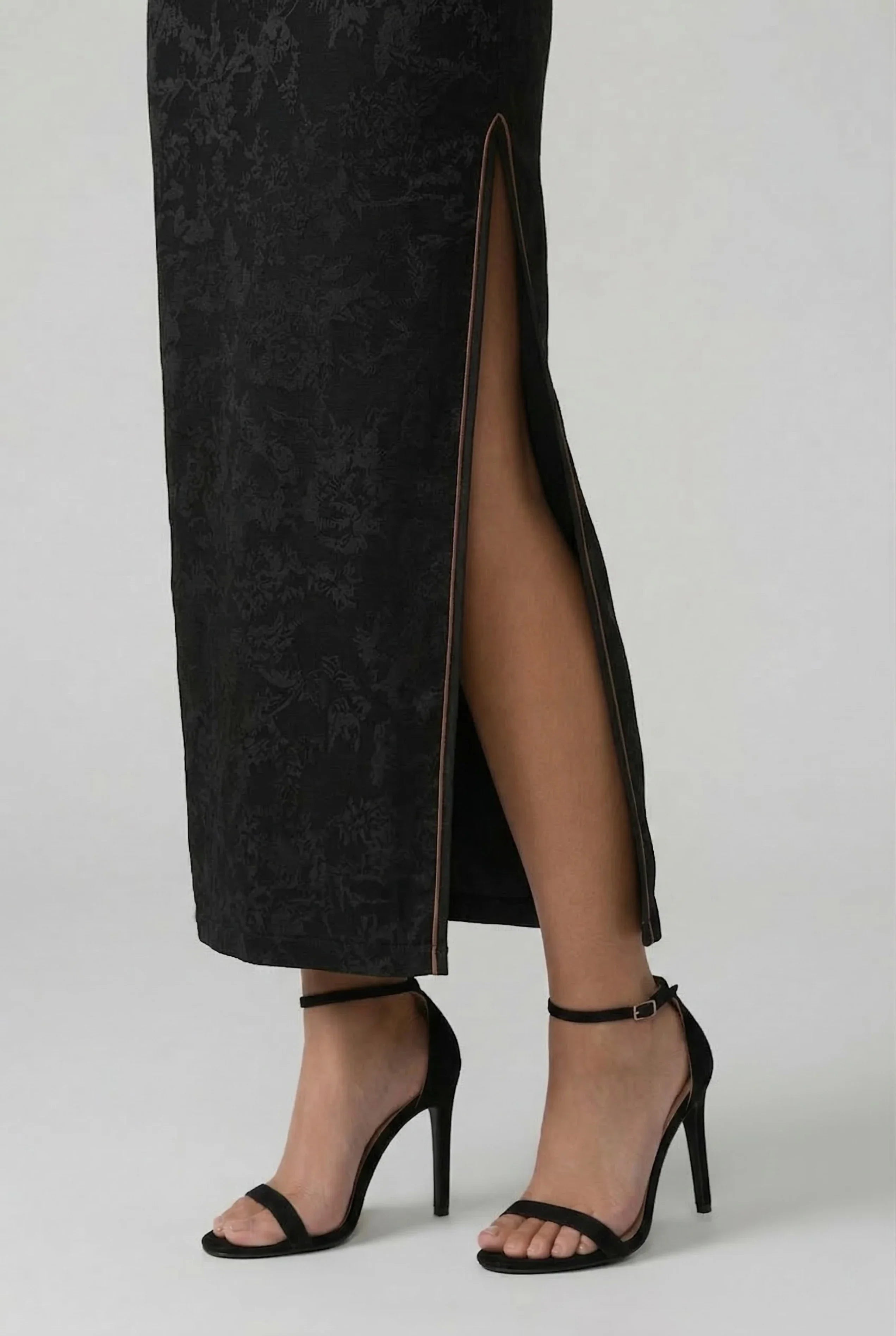 Detailed view of the elegant high side slit of a black Cheongsam dress showing the fabric drape.