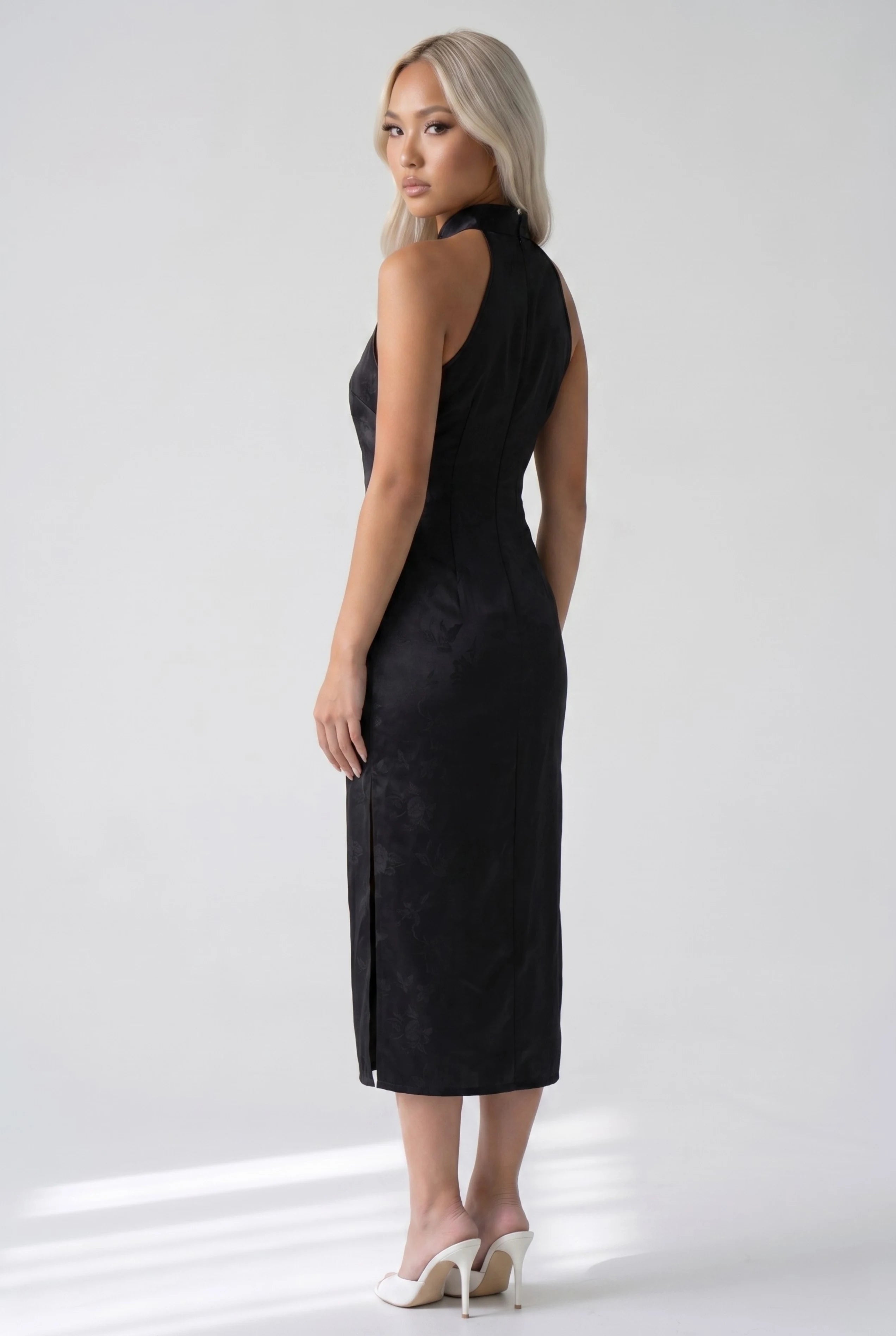 Three-quarter back profile view highlighting the form-fitting design of the black floral jacquard cheongsam