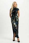A woman with blonde hair posing in a long black velvet qipao dress featuring vibrant blue and gold floral sequin embroidery
