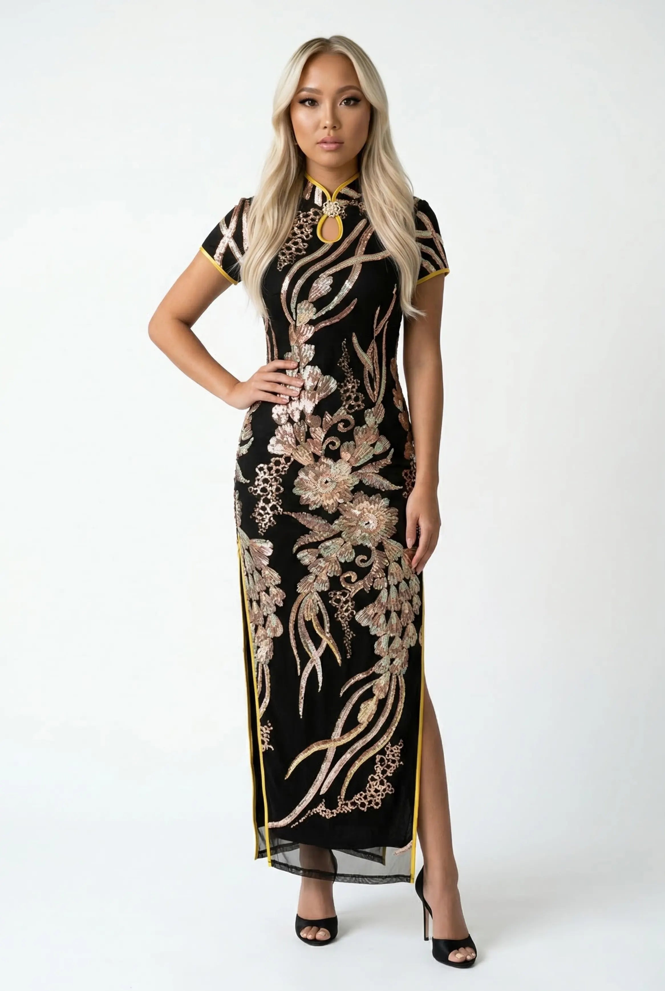 Full-length front view of a luxury black Qipao dress with heavy gold sequin embroidery and yellow contrast piping.
