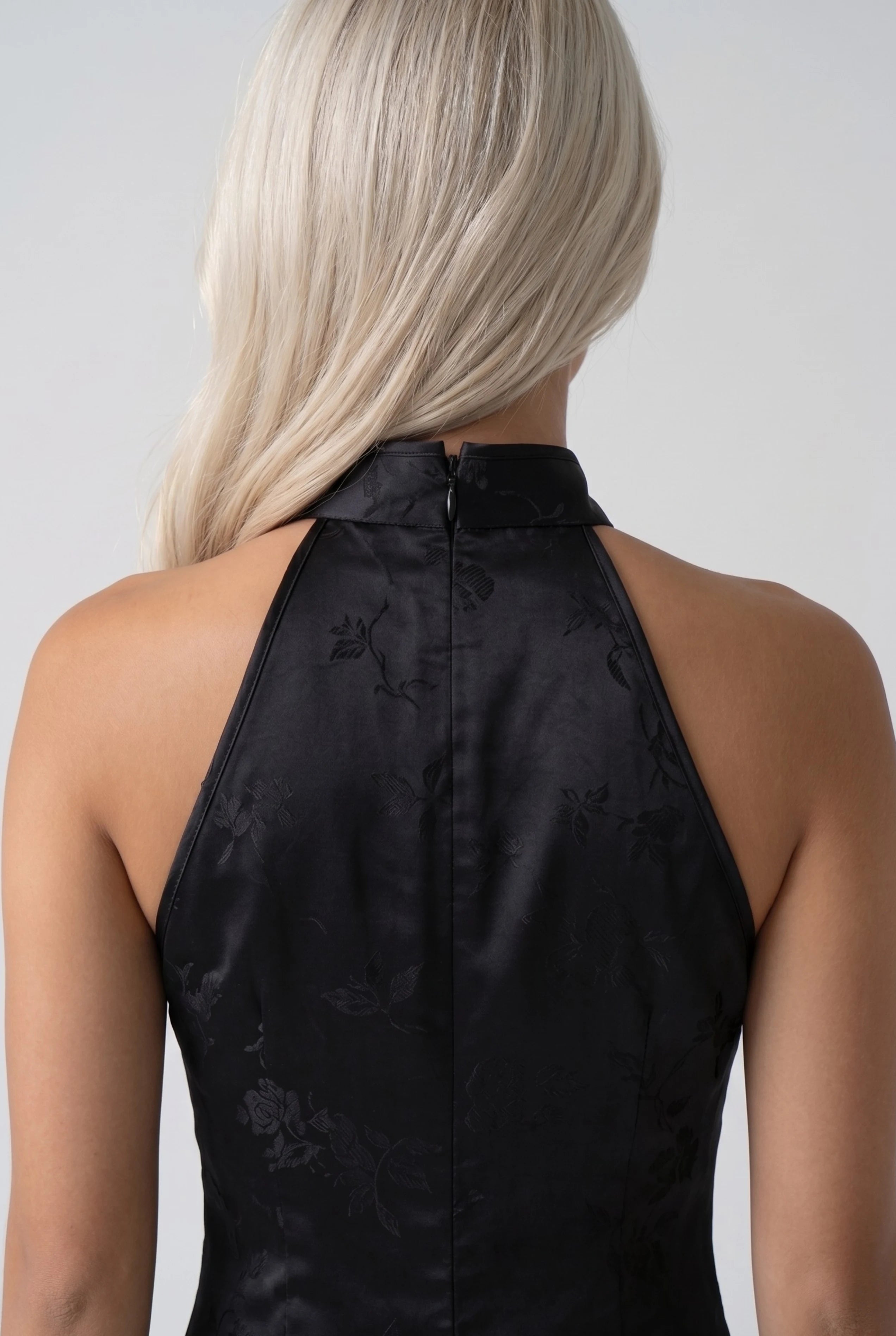Close-up back view showing the high halter collar closure and smooth black satin fabric texture