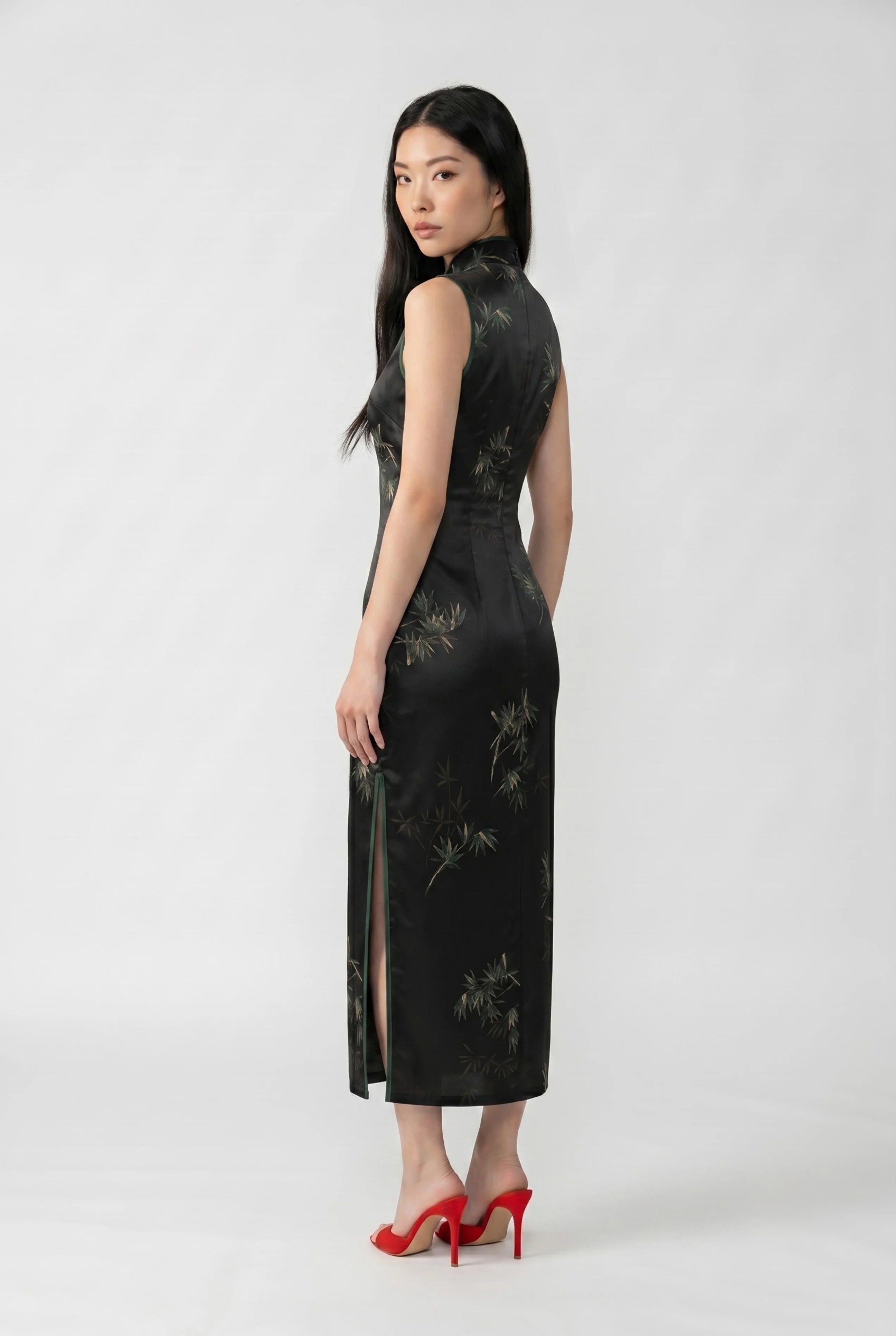 Three-quarter back profile view highlighting the form-fitting design and side slit of the black satin qipao