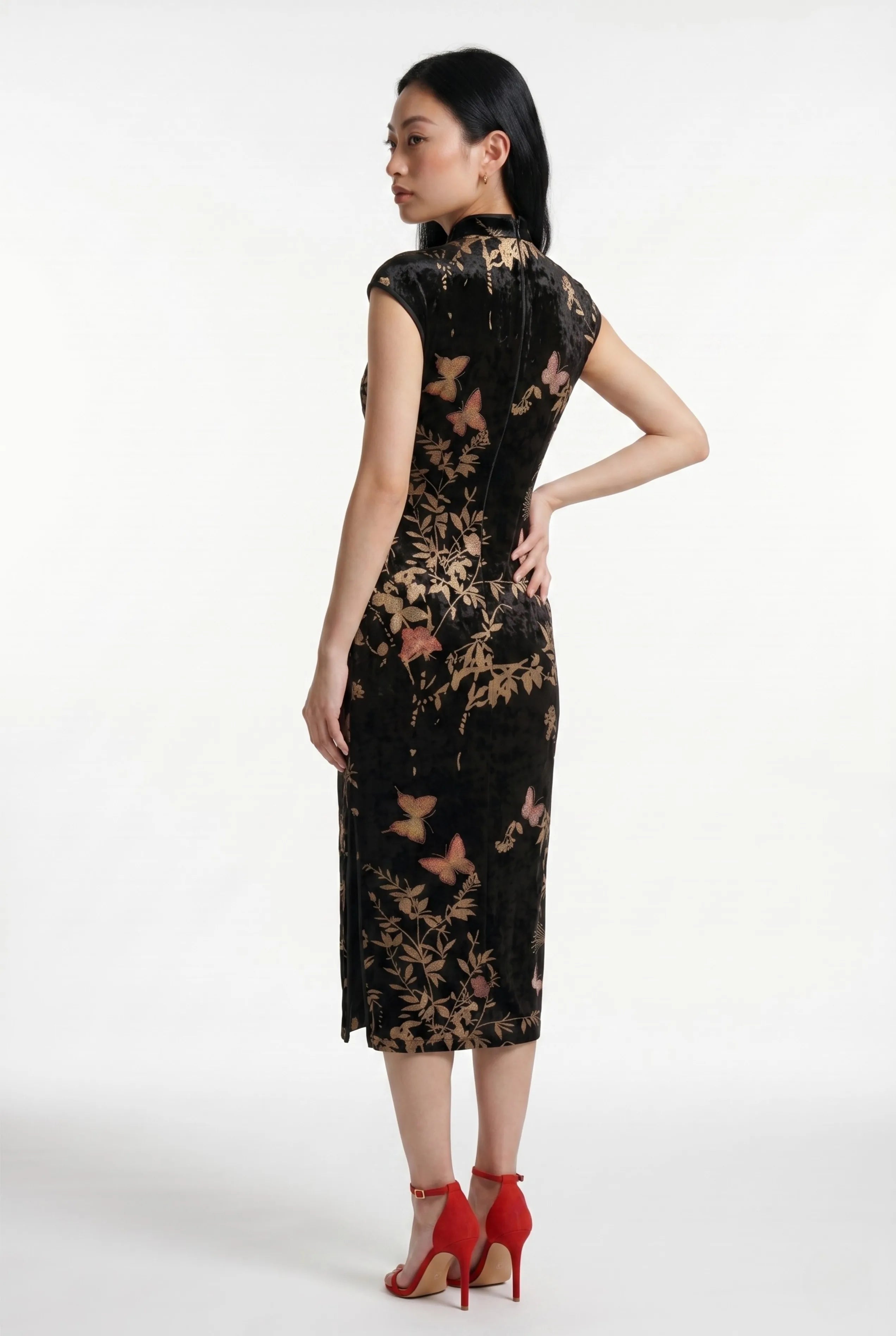 Three-quarter back profile view highlighting the form-fitting design of the black velvet cheongsam