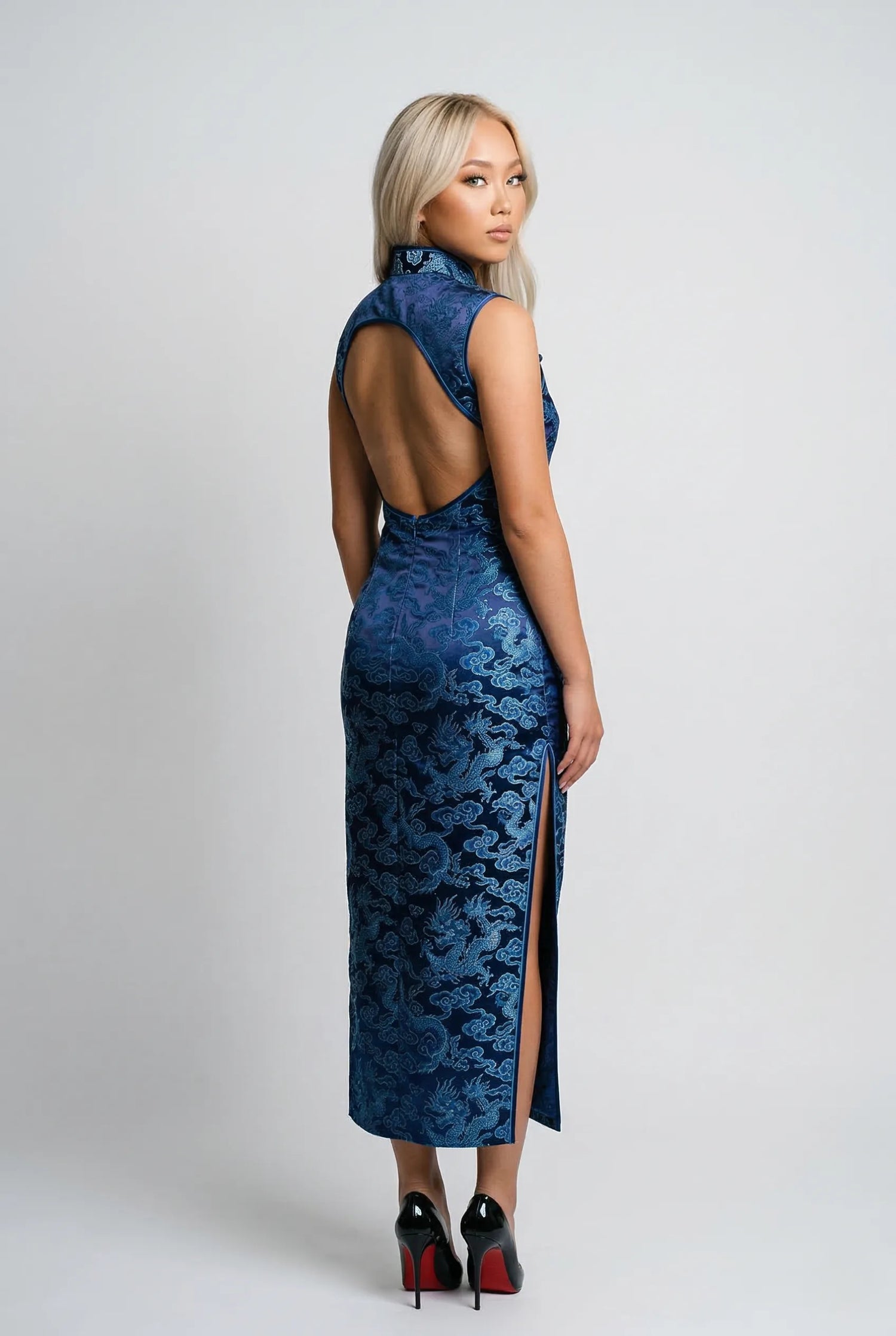 Model wearing an elegant azure and indigo blue qipao by Maison Hua, featuring a circular open-back design, high Mandarin collar, and high-density silk brocade patterns