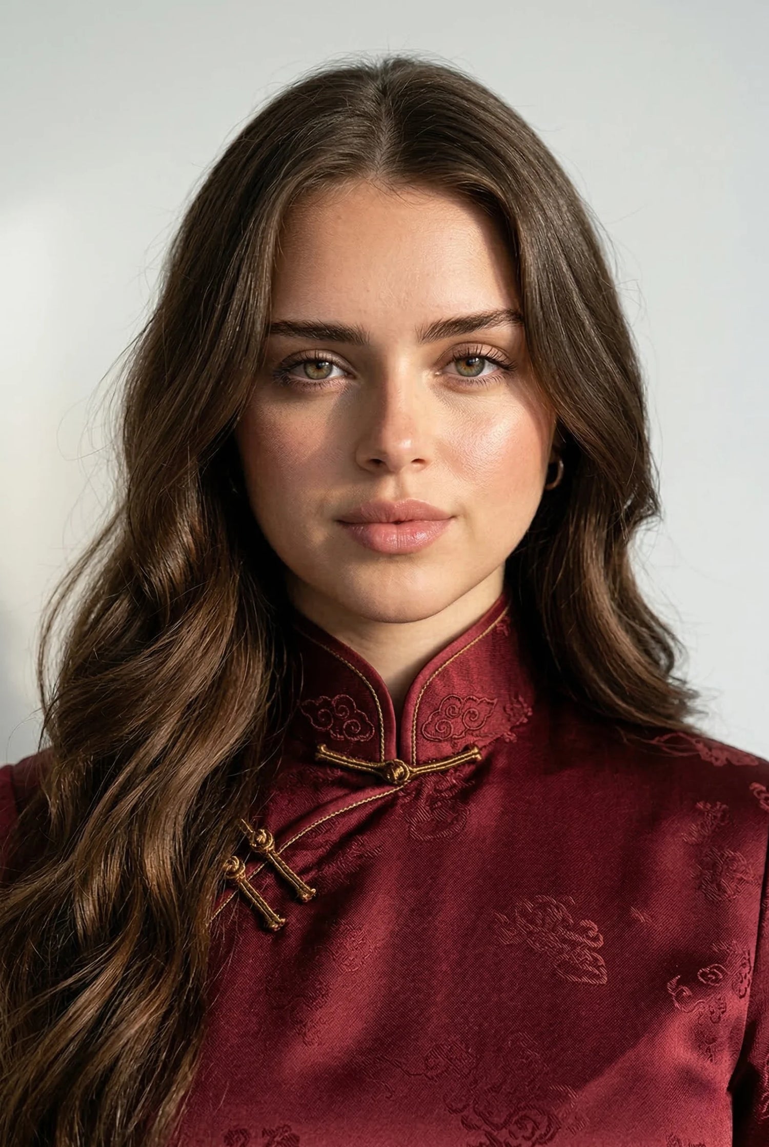 Close-up of a burgundy silk qipao by Maison Hua, highlighting the rigid, padded Mandarin collar and traditional gold knot closures for a heritage silhouette.