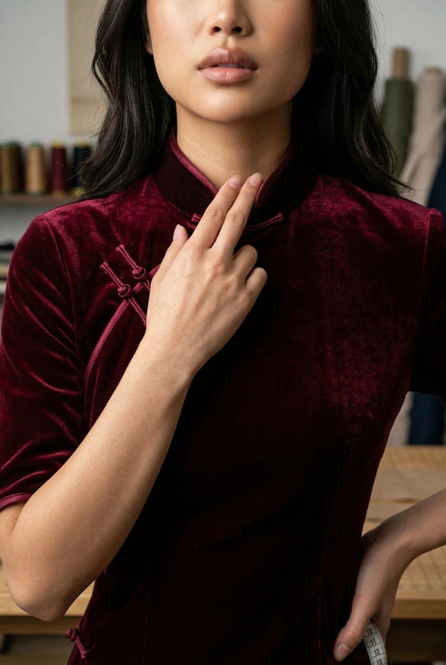 Close-up of a burgundy velvet qipao demonstrating the two-finger collar rule and professional measuring techniques for thick heritage textiles by Maison Hua