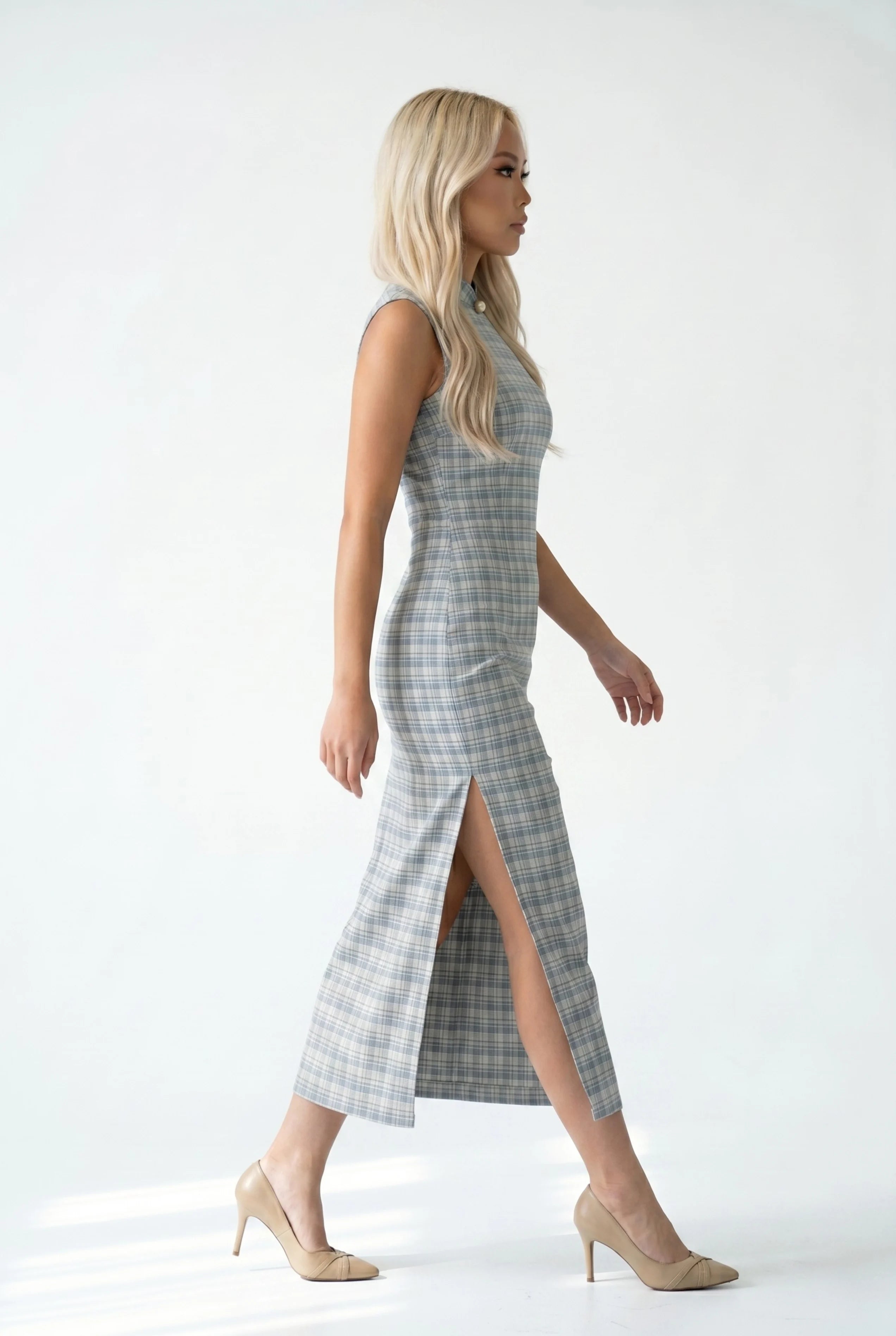 Side profile view of a woman walking in the checkered cheongsam, showcasing the high side slit