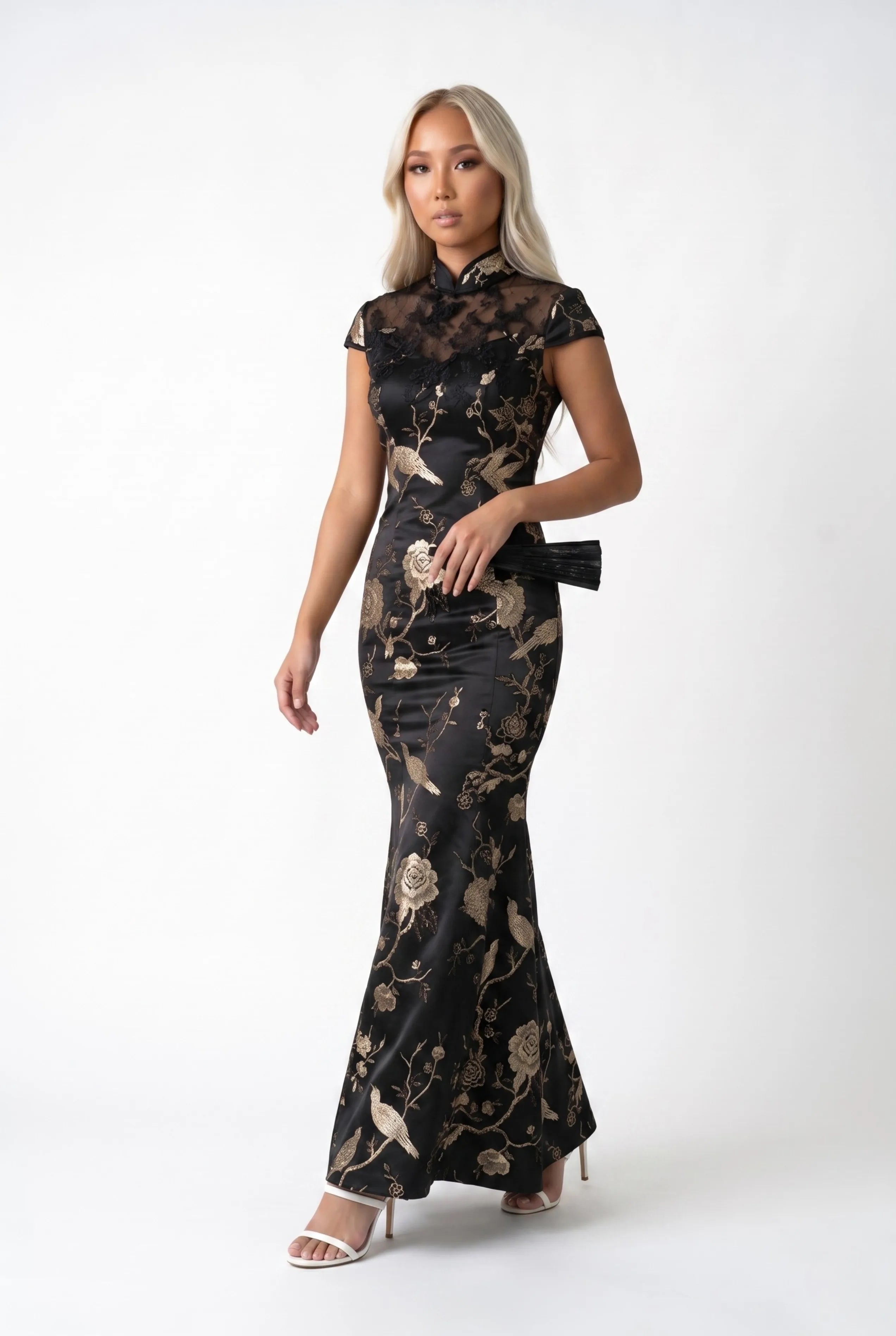 Full-body view of a woman walking in the long black cheongsam dress while holding a small clutch