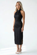 Front full-length view of a halter neck black cheongsam with a subtle floral jacquard pattern and white heels