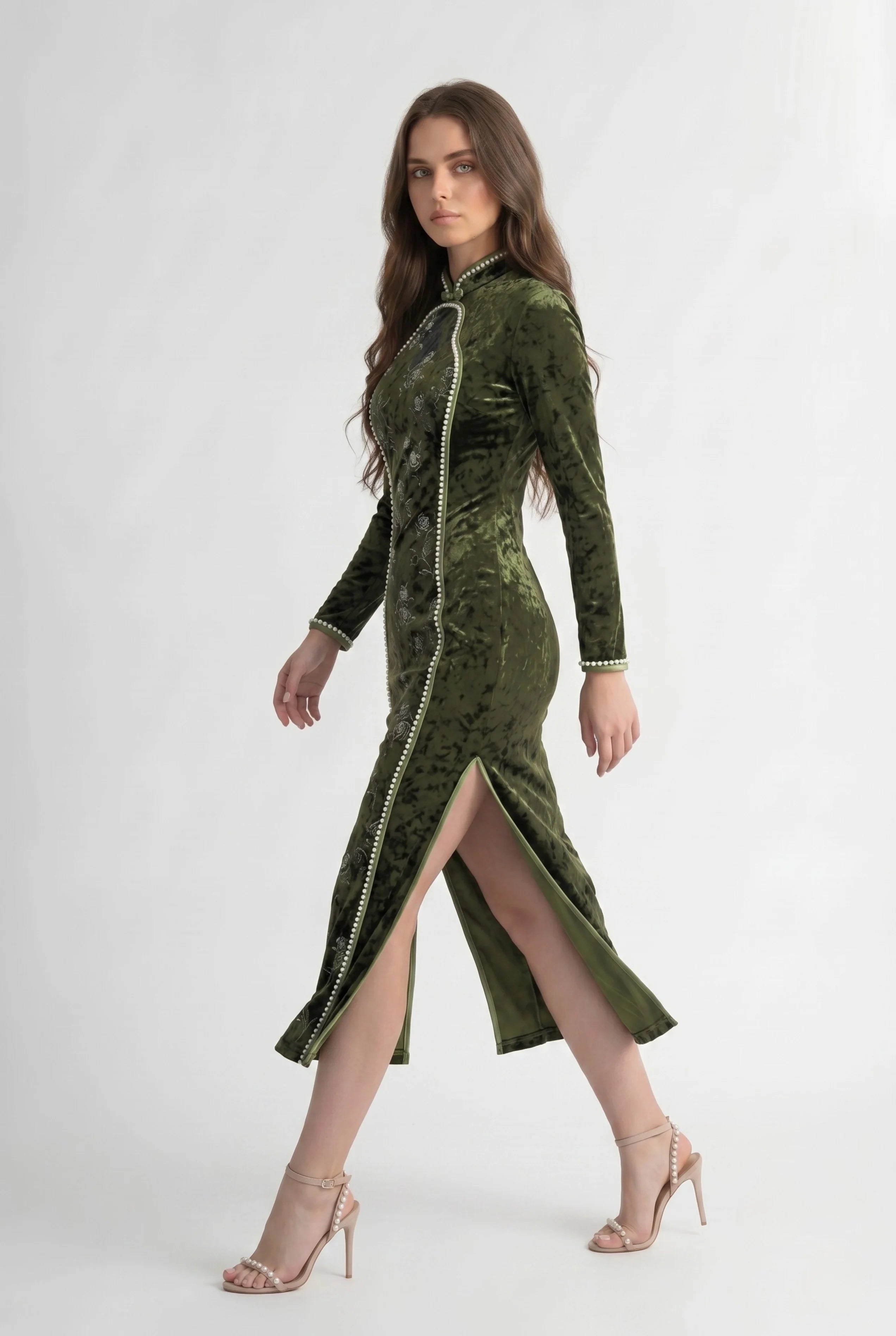 Side profile view of a woman walking in the long sleeve olive velvet Chinese dress, showcasing the high side slit
