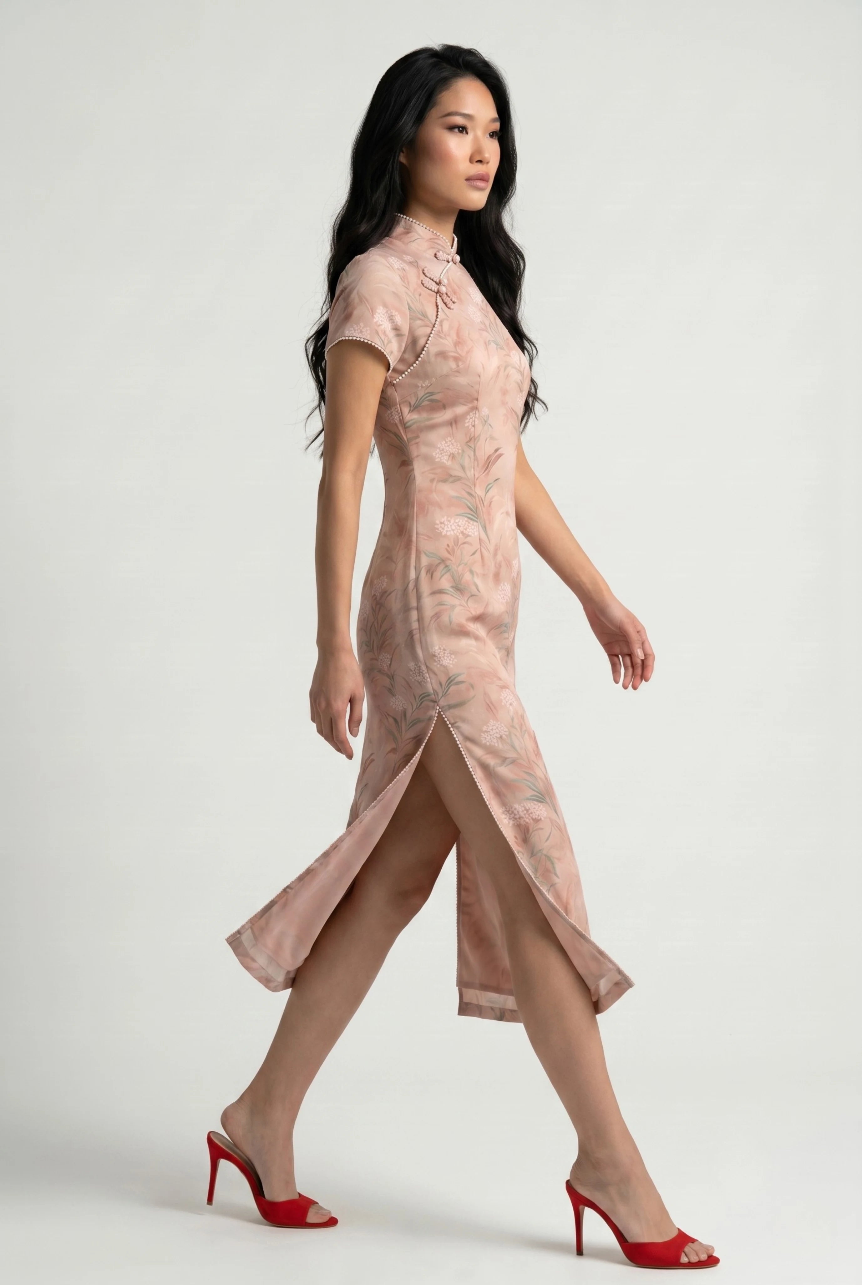 Side profile view of a woman walking in the pink floral Chinese dress, showcasing the high side slit and red open-toe heels
