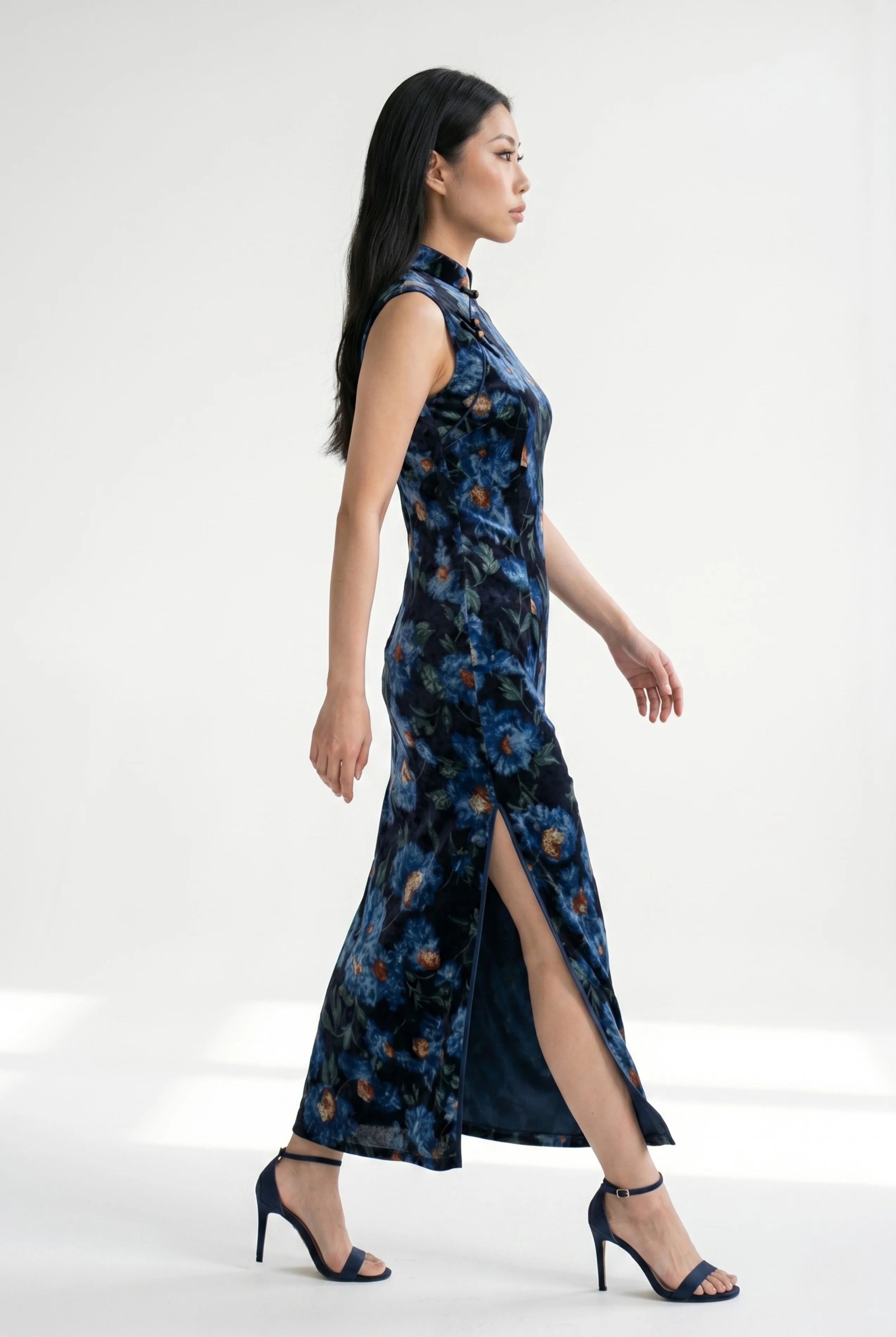 Side profile view of a woman walking in the velvet Chinese dress, showcasing the high side slit