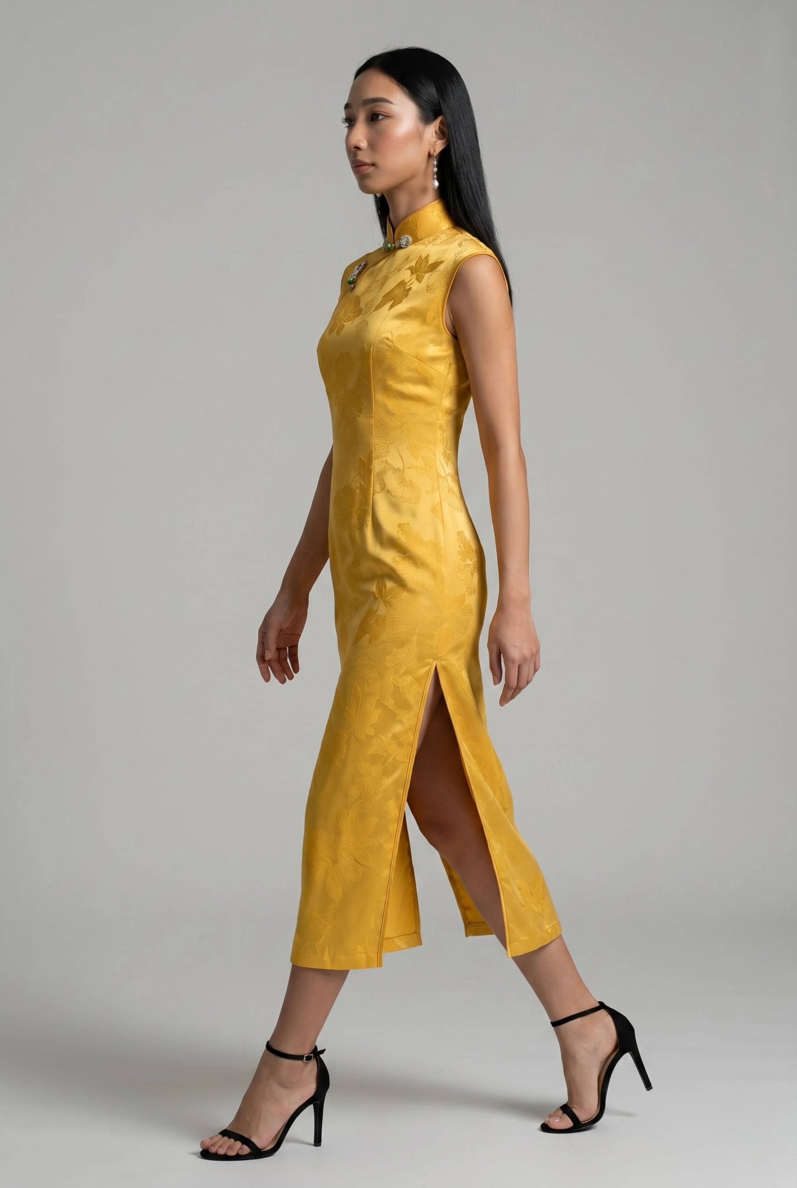 Side profile view of a woman walking in the yellow velvet Chinese dress, showcasing the high side slit