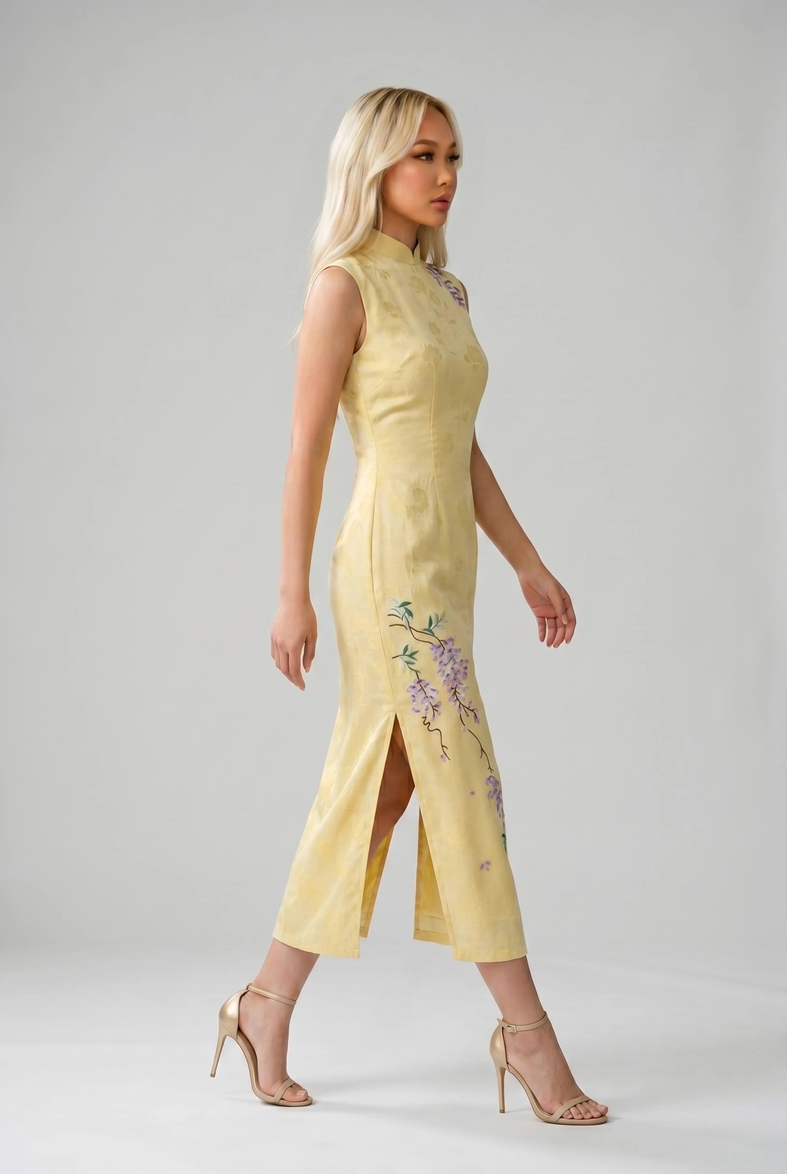 Side profile view of a woman walking in the yellow Chinese qipao, showcasing the side slit and floral details
