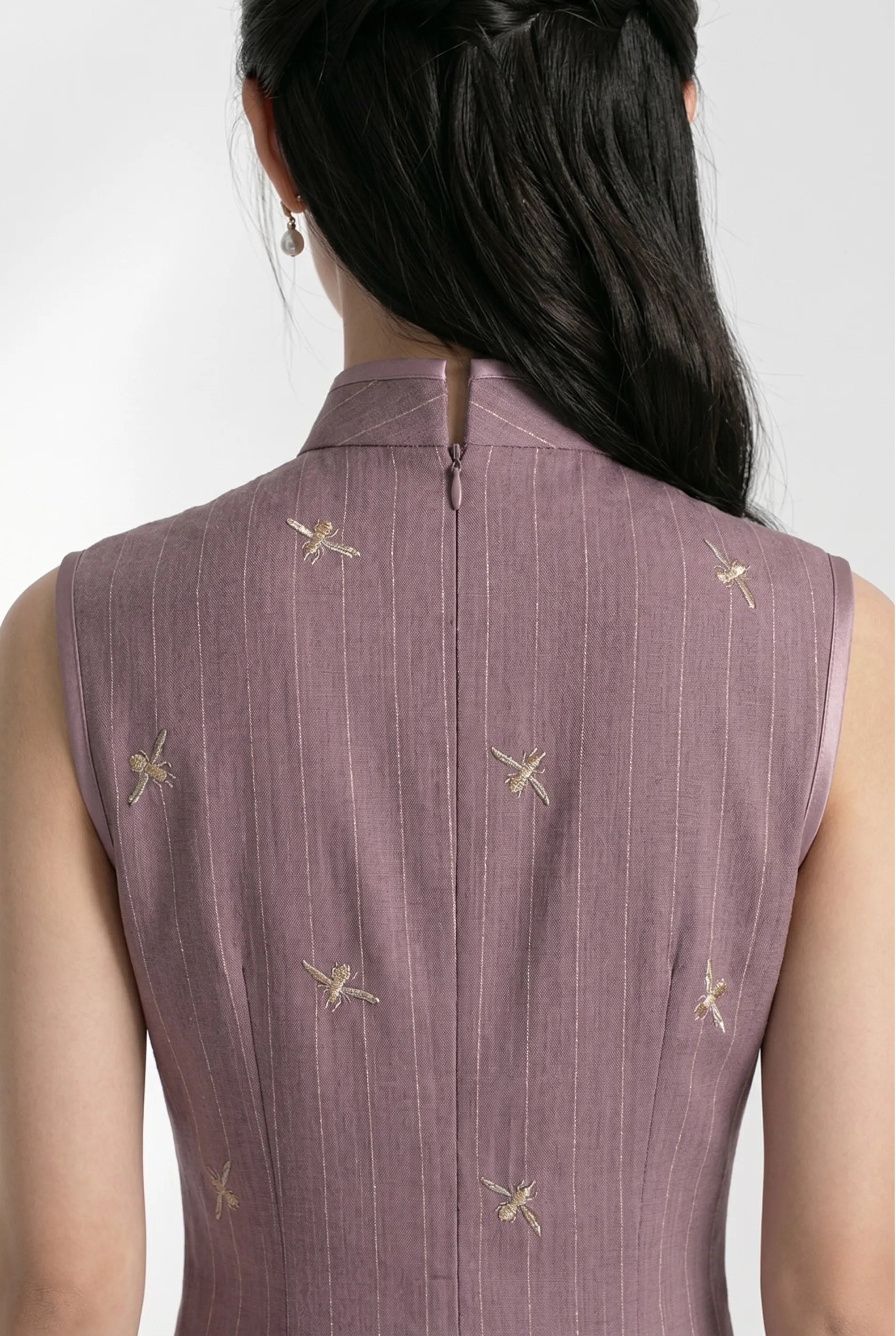 Close-up back view highlighting the high collar and gold embroidered details of the purple Chinese style qipao.