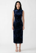 Front view of a sleeveless dark blue velvet cheongsam dress paired with white strappy heels