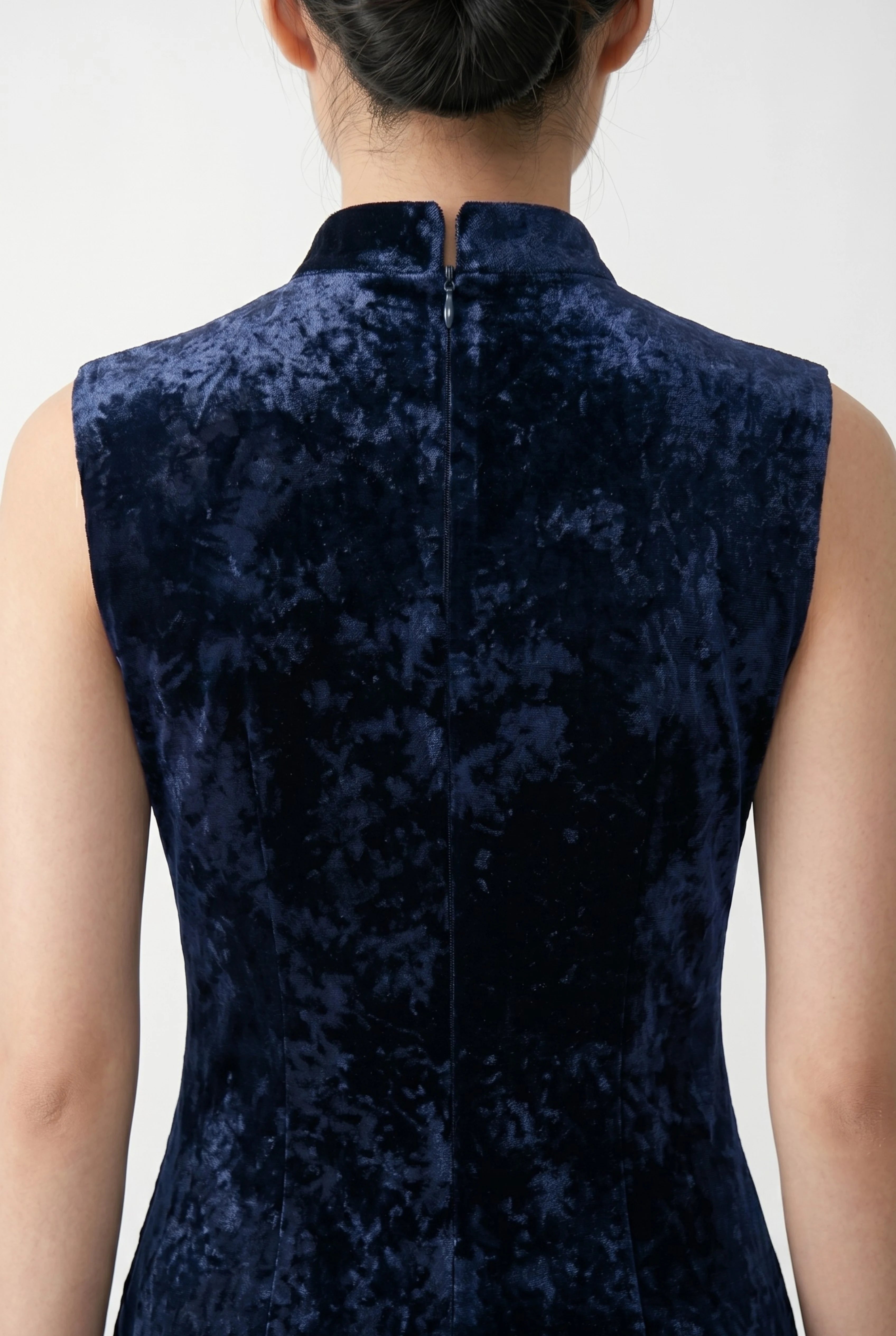 Close-up back view showing the high collar, zipper closure, and rich texture of the dark blue qipao