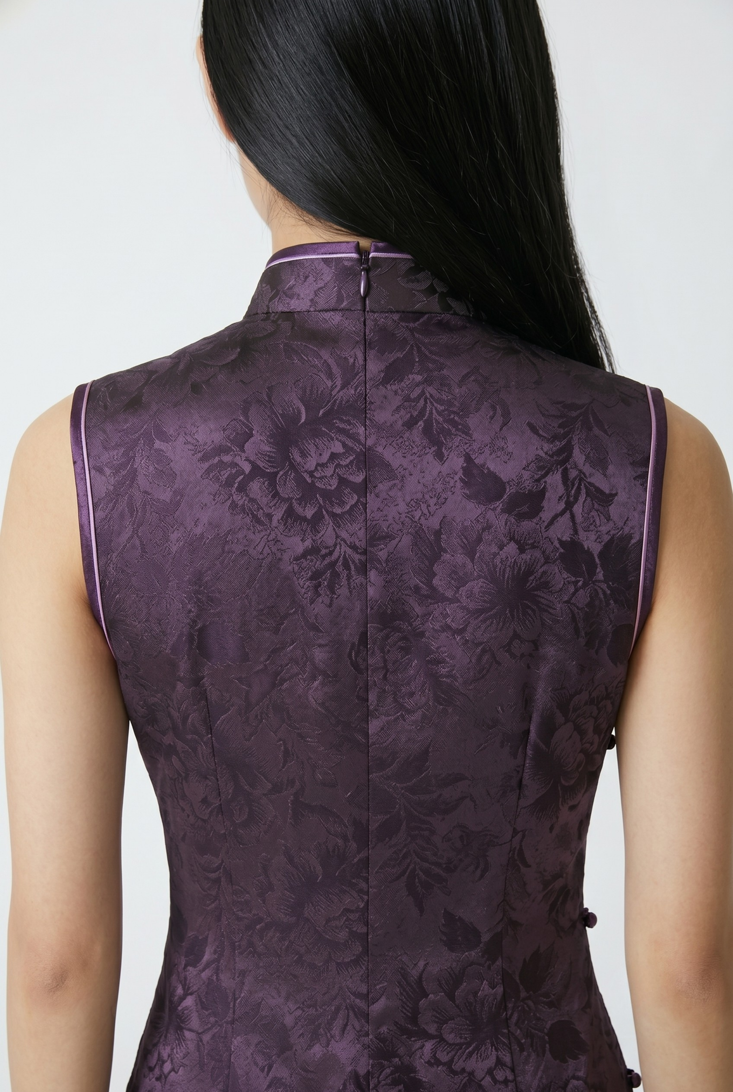 Close-up back view showing the hidden zipper closure, clean shoulder cuts, and rich jacquard texture of the dark purple cheongsam