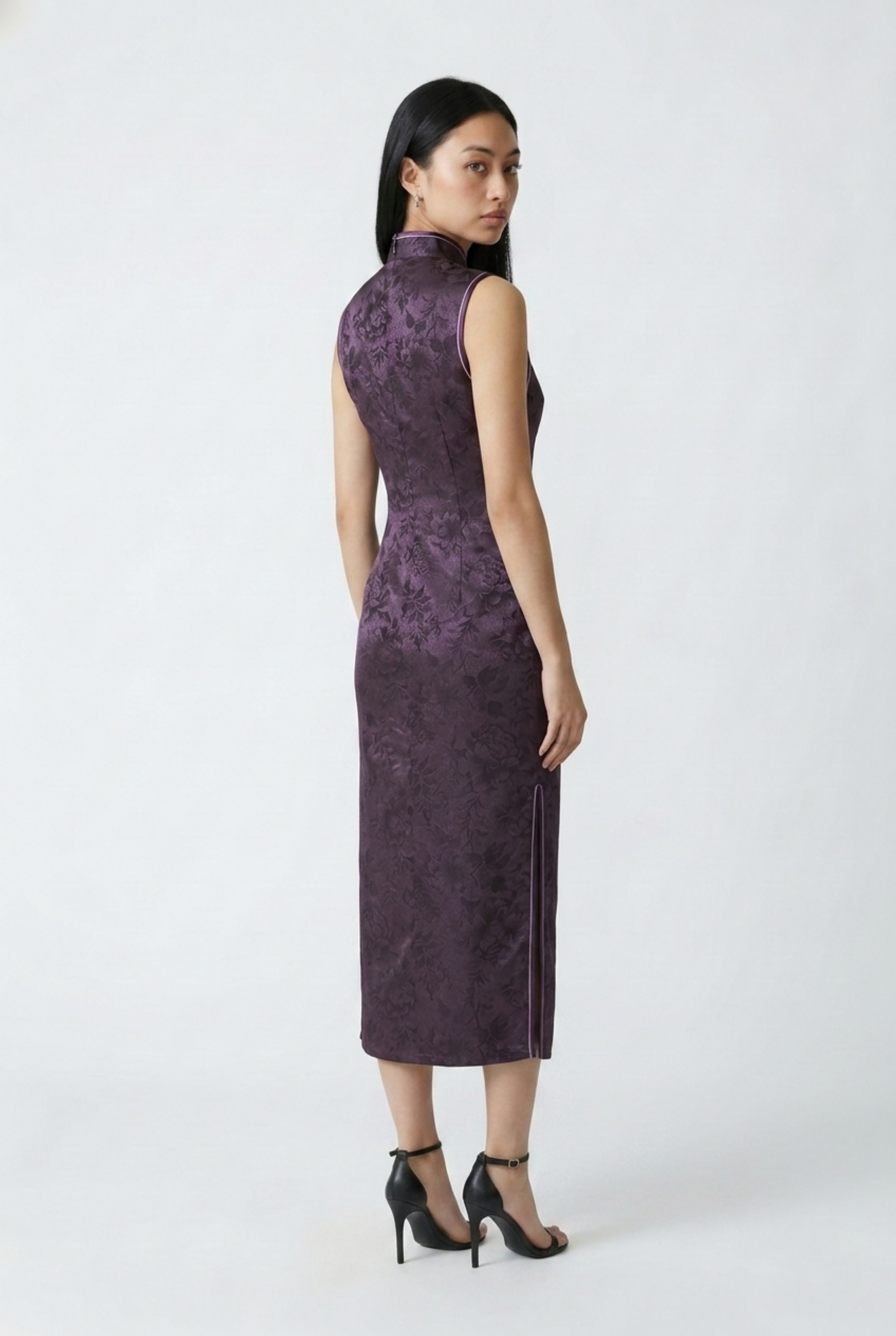 Three-quarter back profile view highlighting the tailored fit and side slit of the dark purple floral jacquard cheongsam