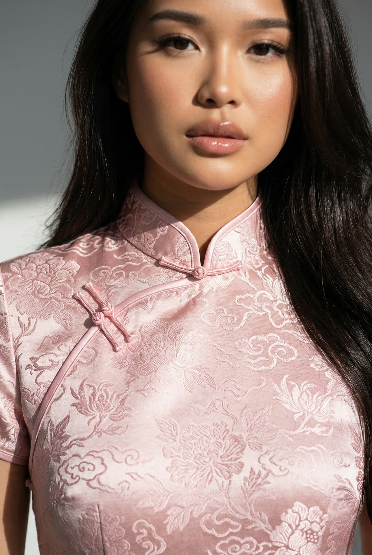 Close-up of a pink Chinese dress in high-density brocade, showcasing the fabric integrity and luster of a light-toned cheongsam
