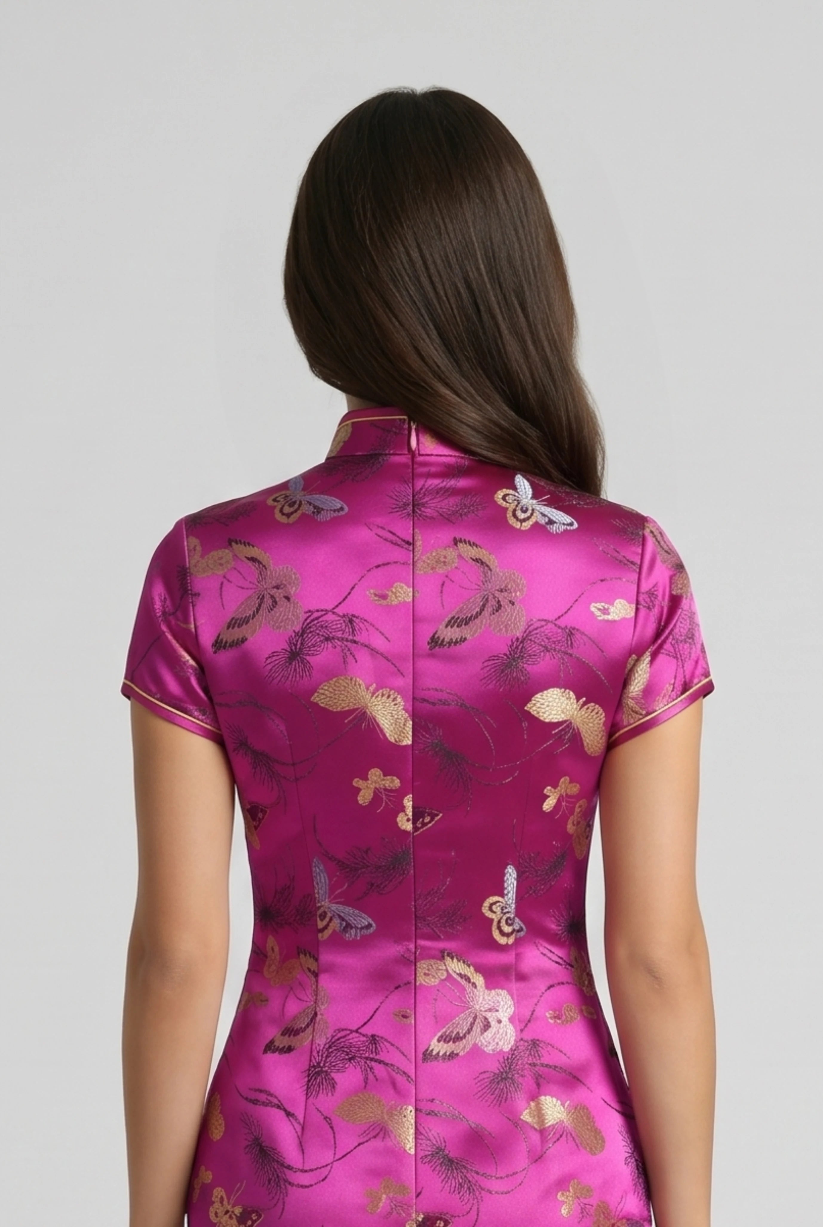 Close-up back view showing the hidden zipper closure, cap sleeve construction, and rich satin pattern on the fuchsia pink cheongsam