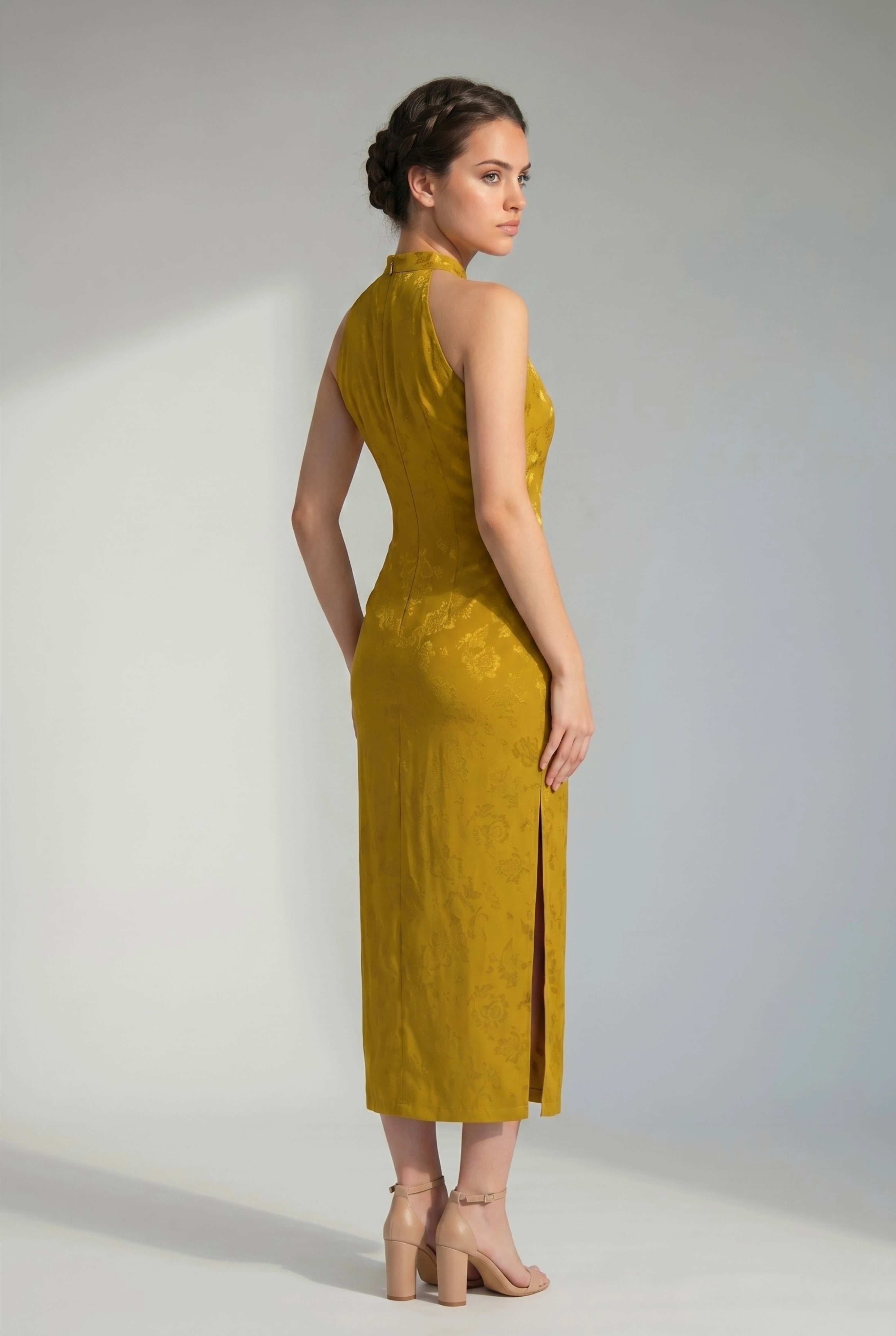Three-quarter side view of a woman posing in a gold cheongsam dress, highlighting the elegant fit