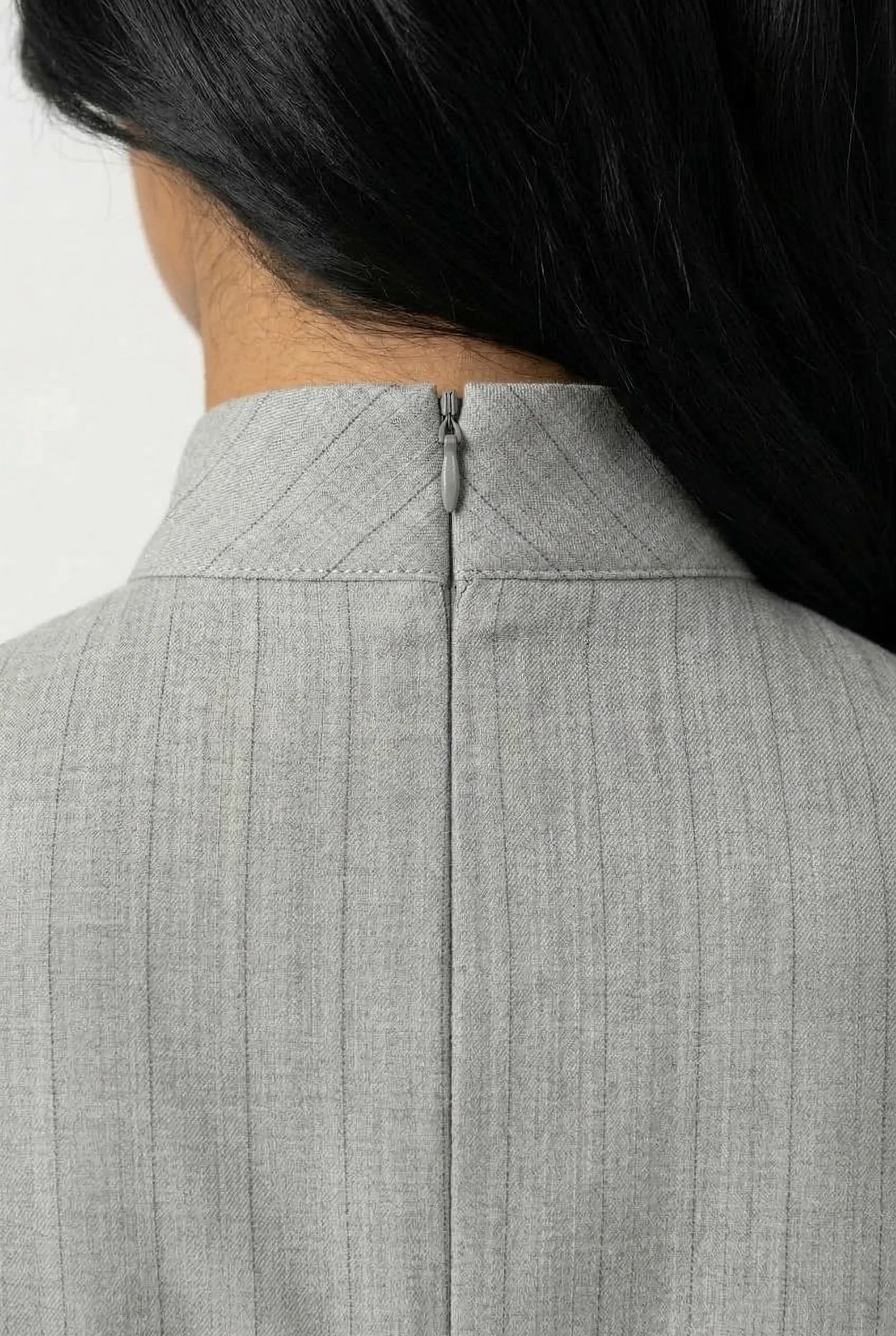 Detailed shot of the back of the mandarin collar with a discreet zipper on a grey sleeveless Cheongsam.