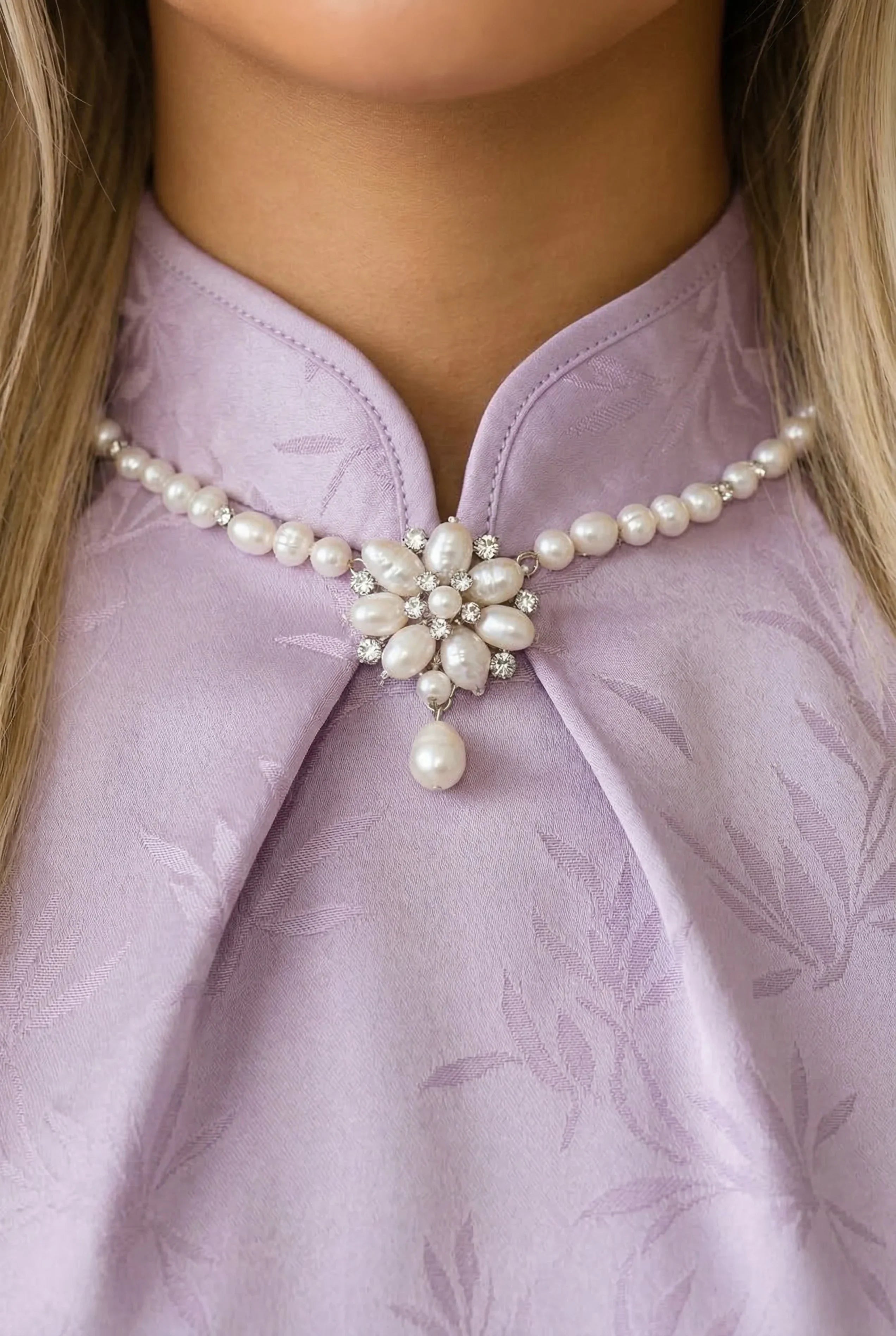 Close-up of the mandarin collar on a lavender Qipao featuring an intricate pearl and beaded flower ornament.