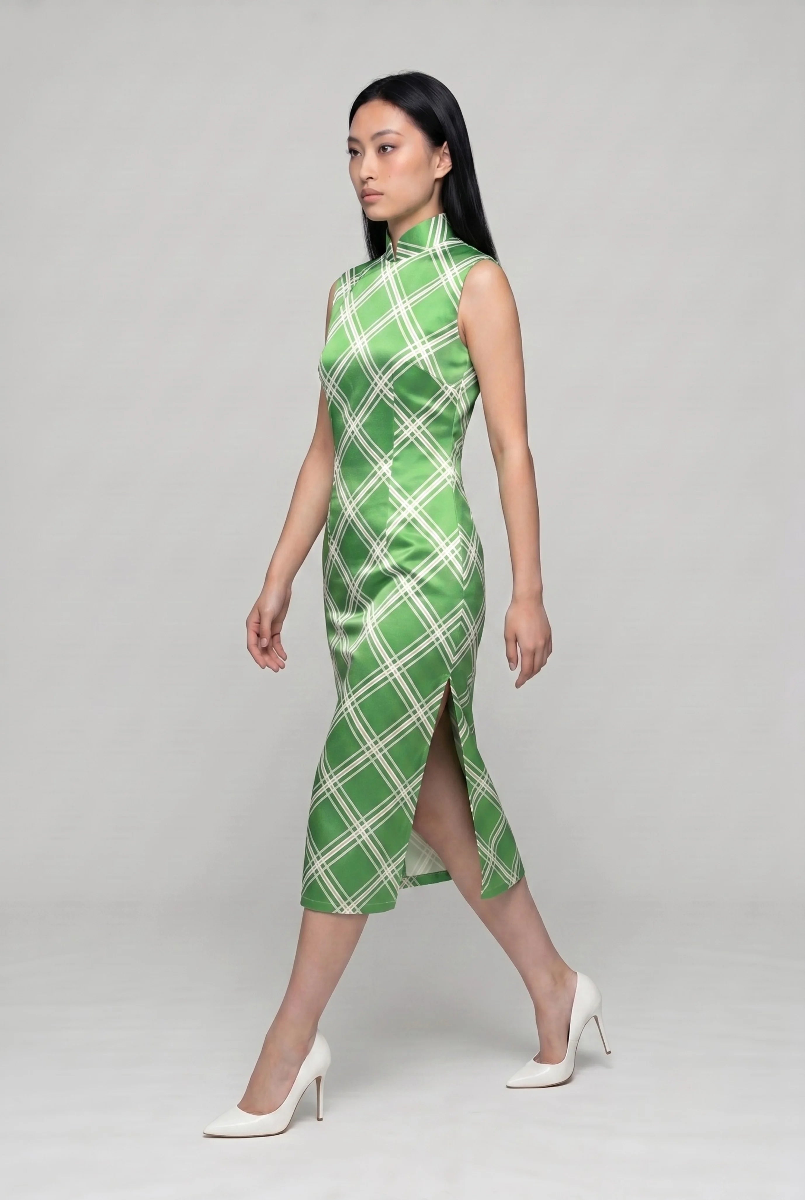 Side profile view of a woman walking in the lime green diamond qipao, showcasing the elegant side slit