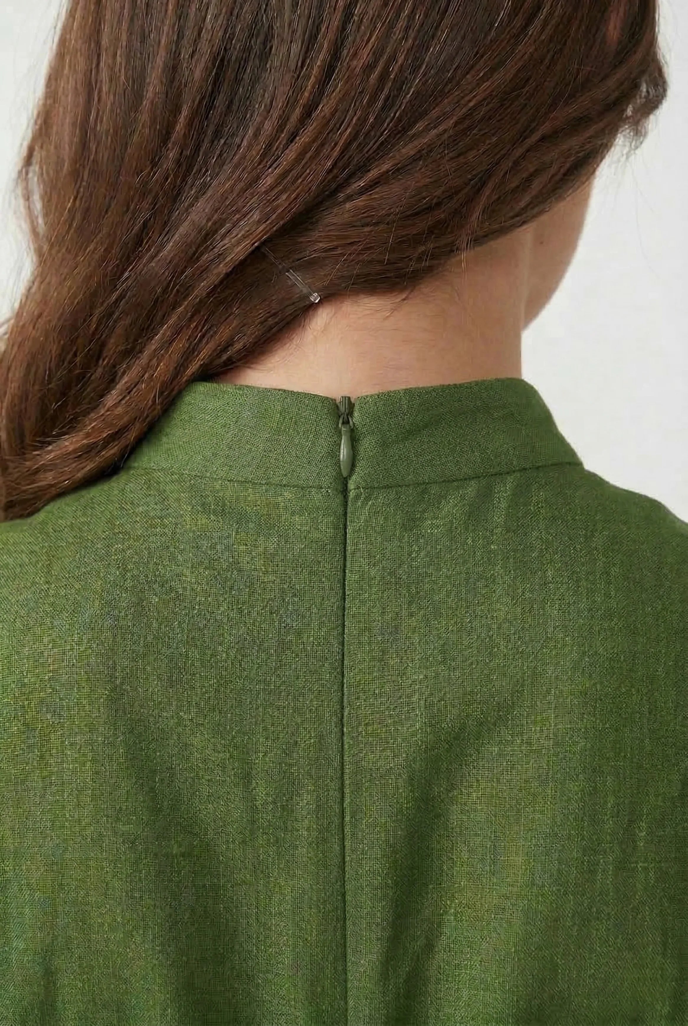 Detailed shot of the high back mandarin collar with a discreet zipper on a casual green linen dress.