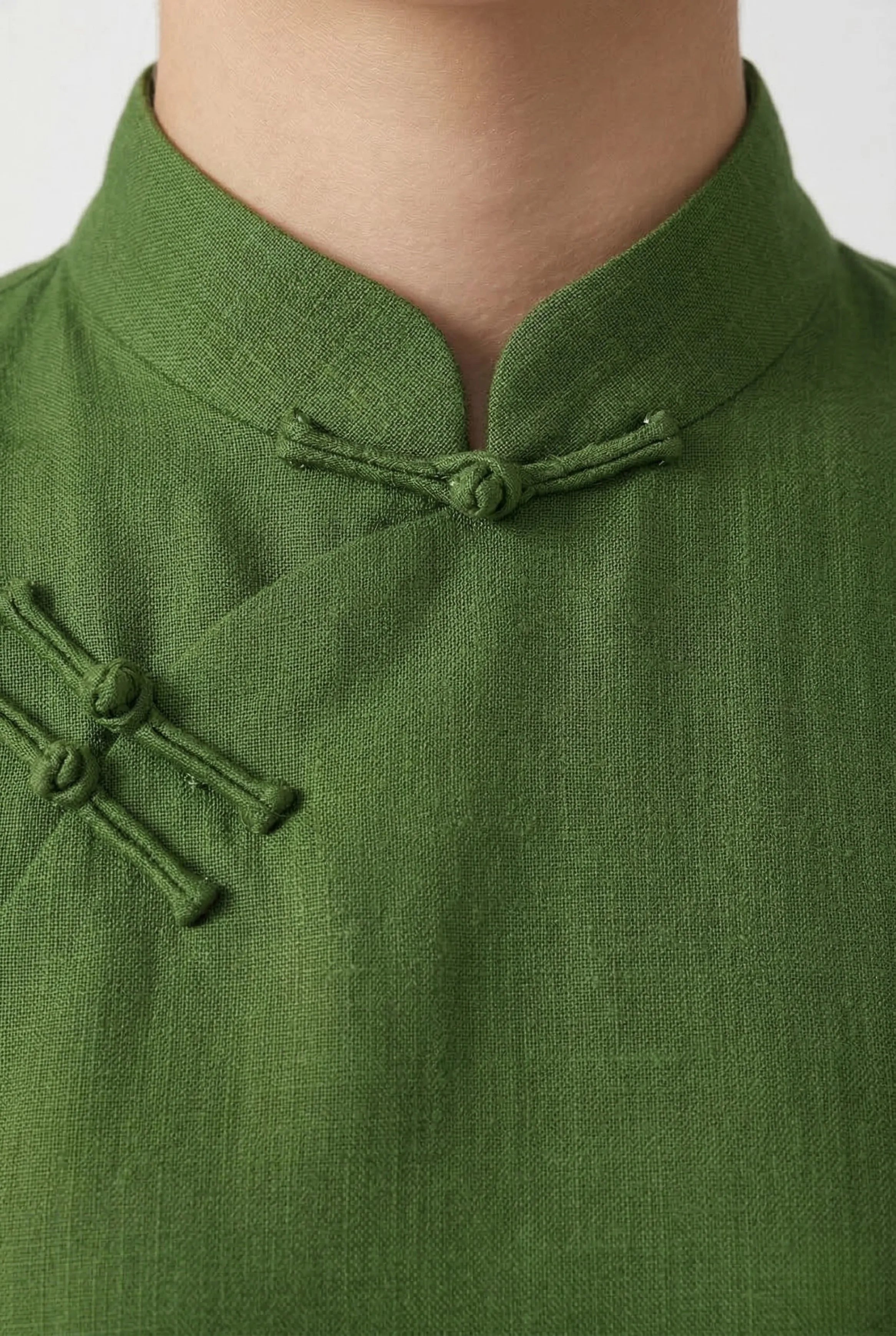 Close-up of the standing mandarin collar and subtle frog button closures on a green textured linen dress.