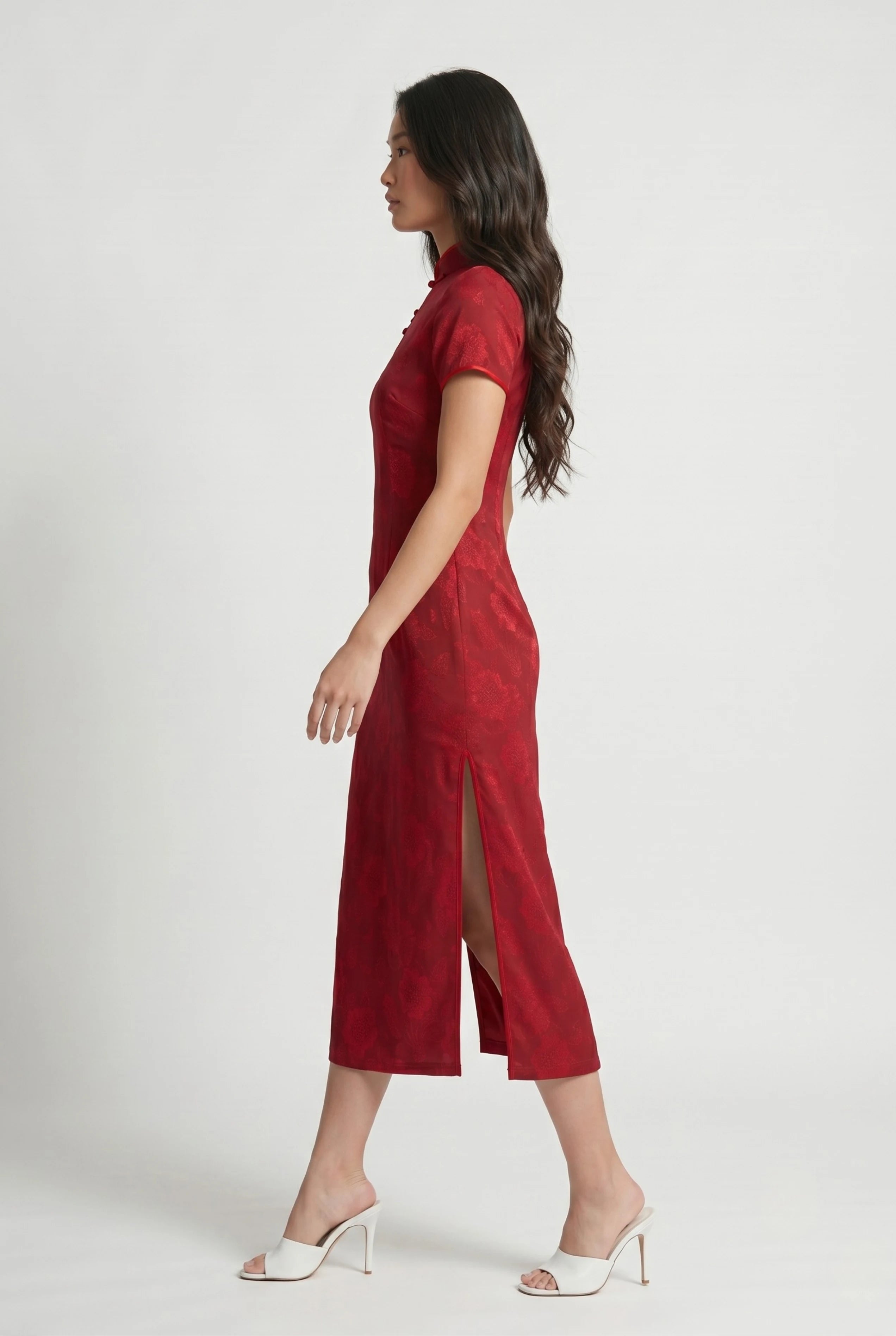 Full-body side profile view of a woman in stride wearing the long red cheongsam dress paired with white heels