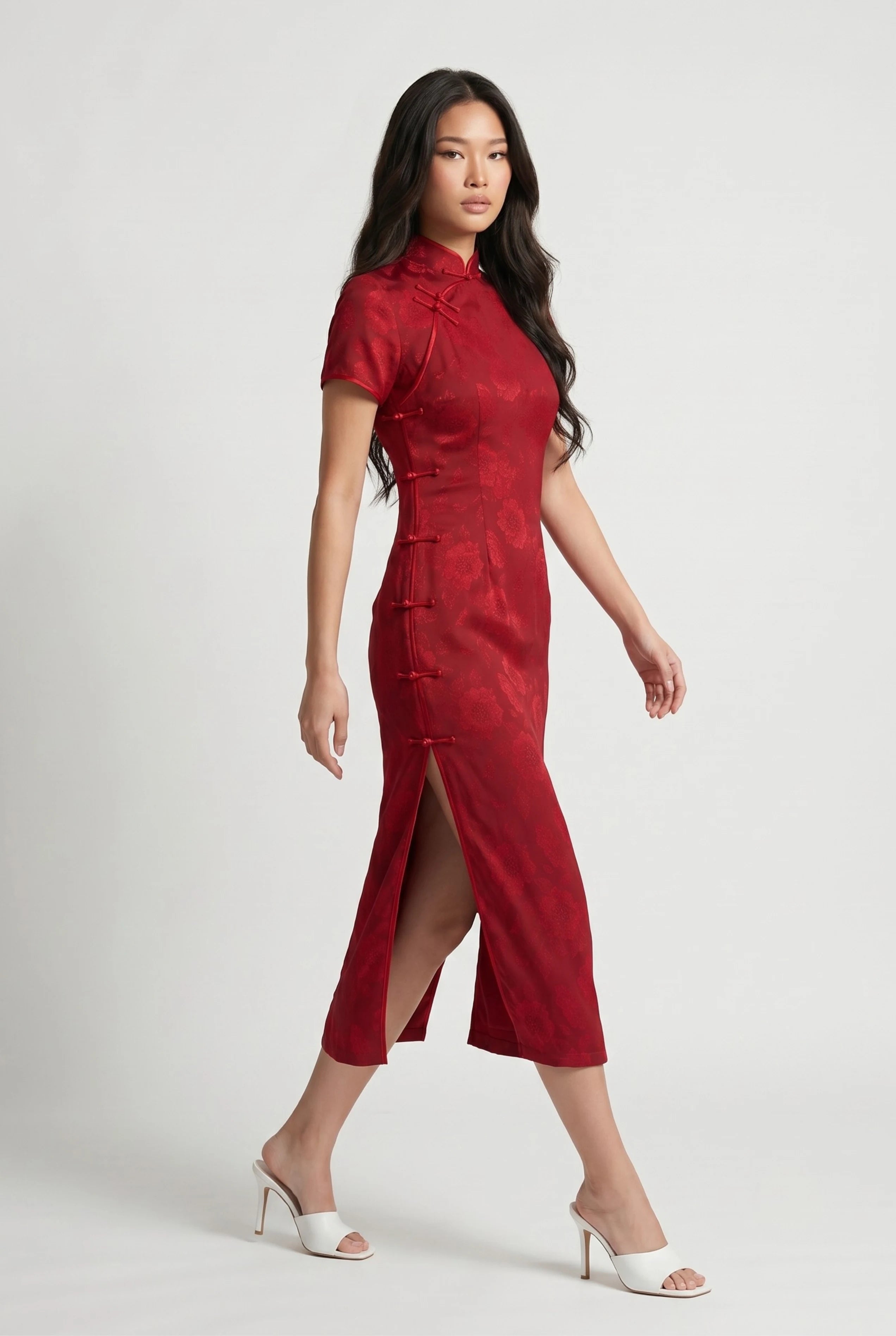 Side profile view of a woman walking in the long red cheongsam dress, showcasing the high side slit