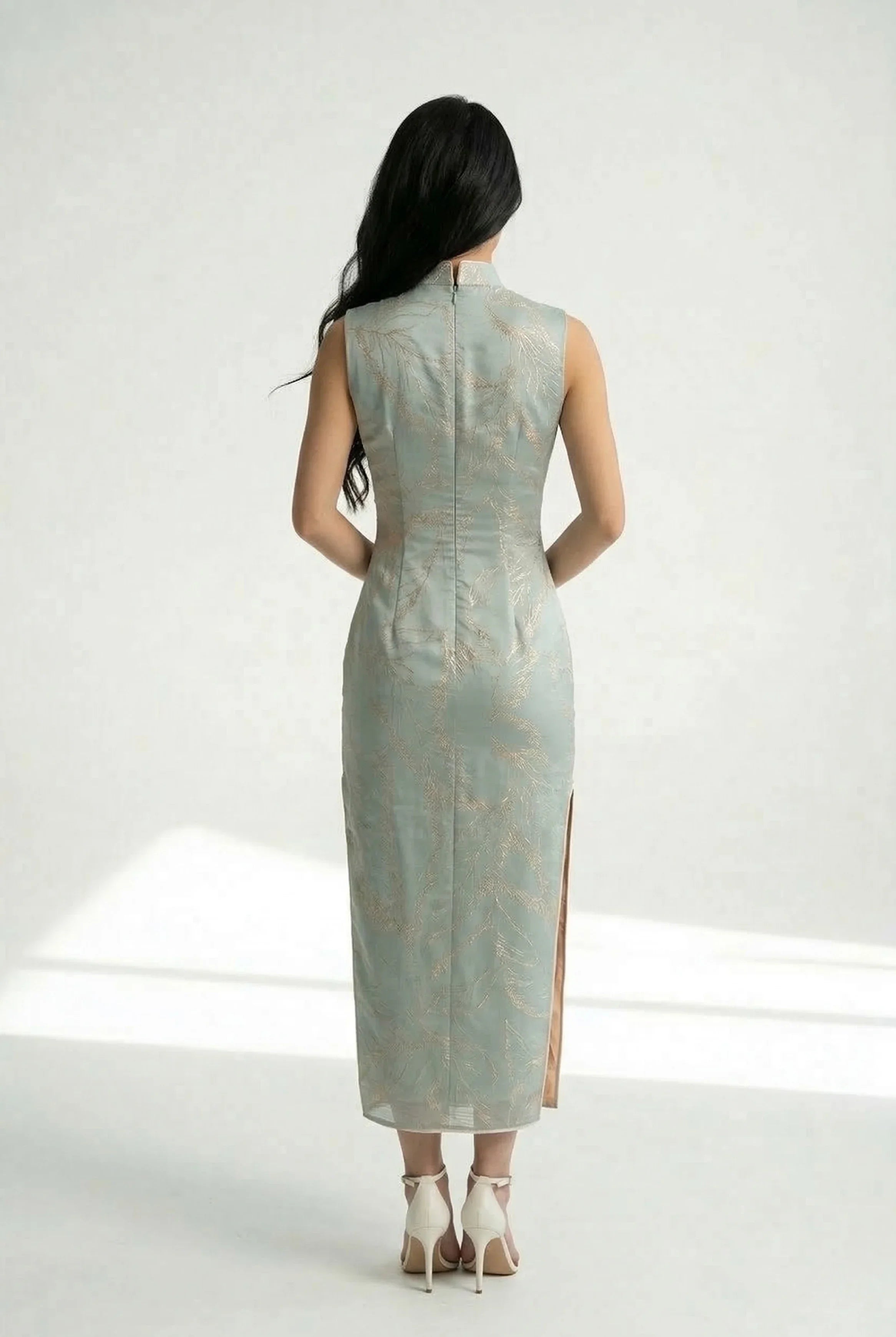 Back view of a long, form-fitting sage blue Cheongsam dress showing the elegant silhouette and gold botanical embroidery.