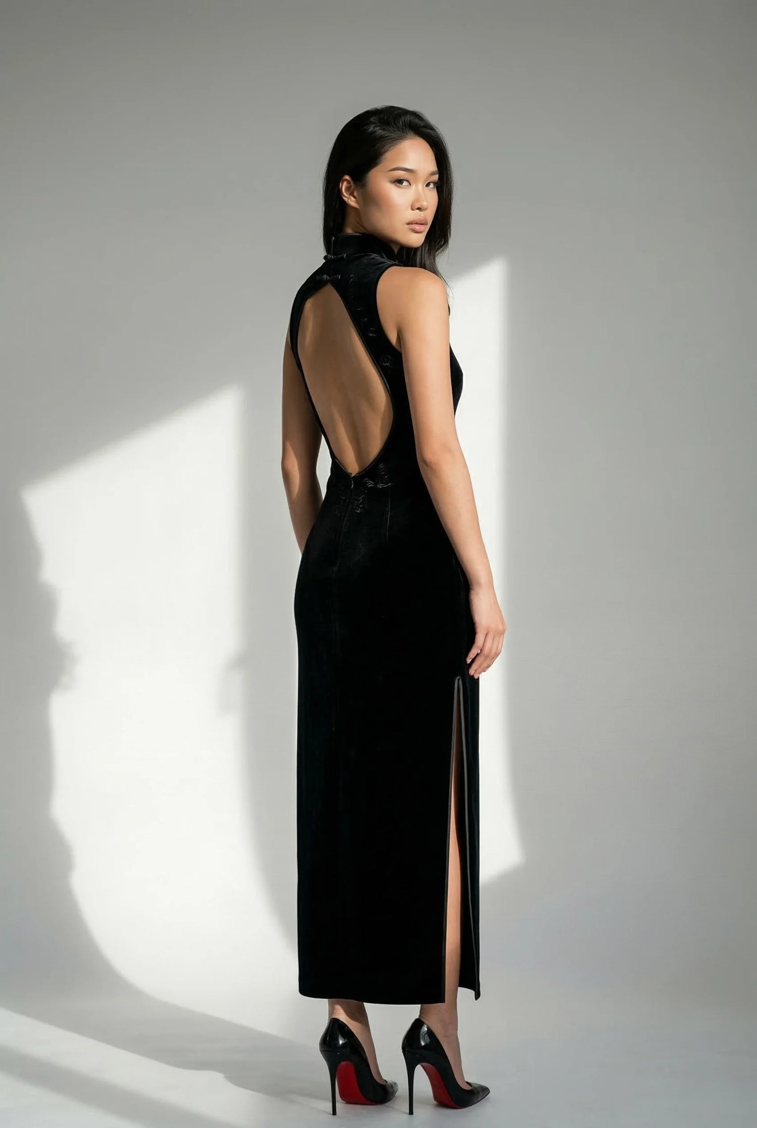 Sleek black high-density silk and brocade Qipao dress by Maison Hua, featuring a traditional Mandarin collar, thigh-high slit, and a modern circular open-back design for formal high-stakes events
