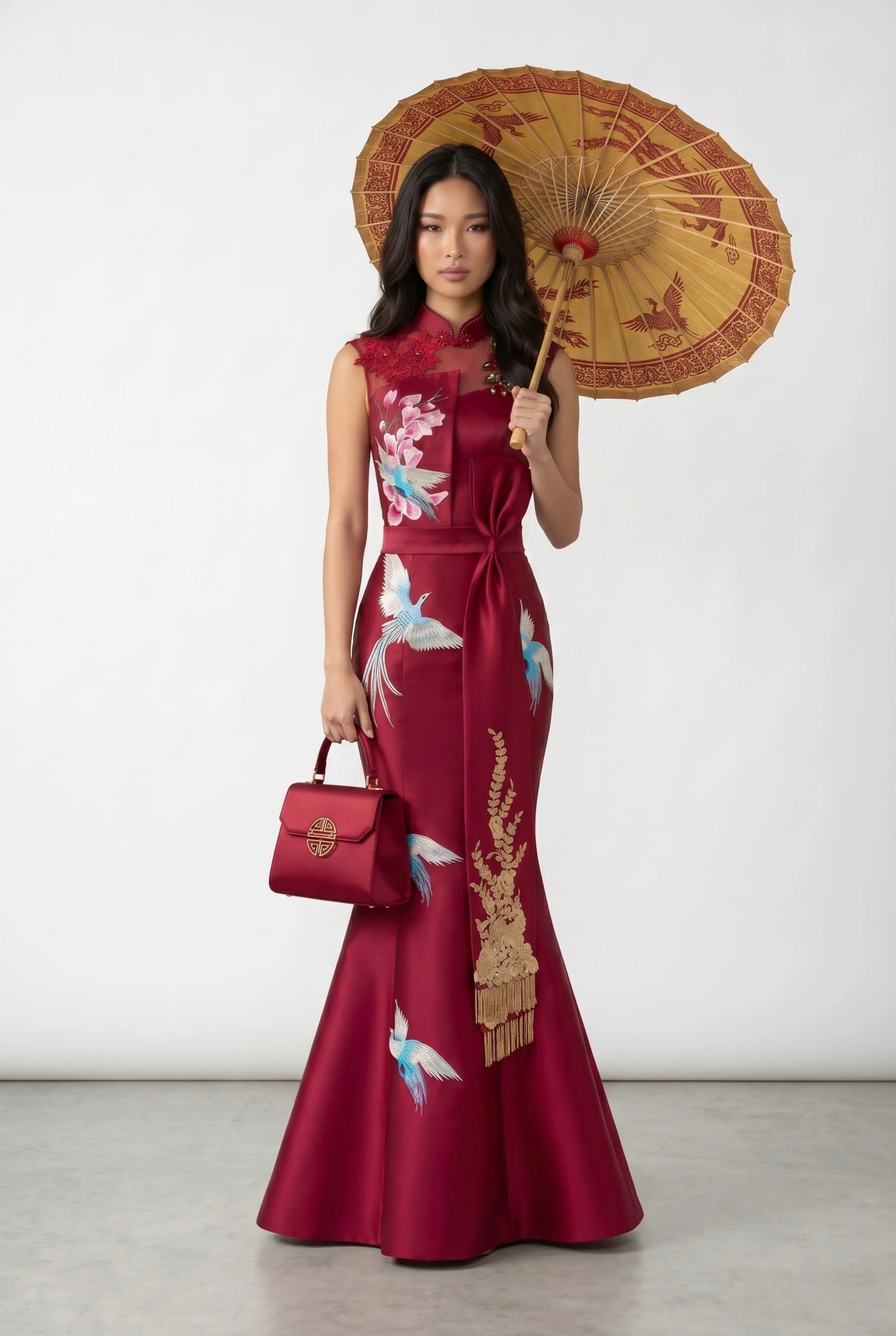 Full-length view of a woman posing in the red mermaid qipao while holding a traditional oil-paper umbrella and matching handbag