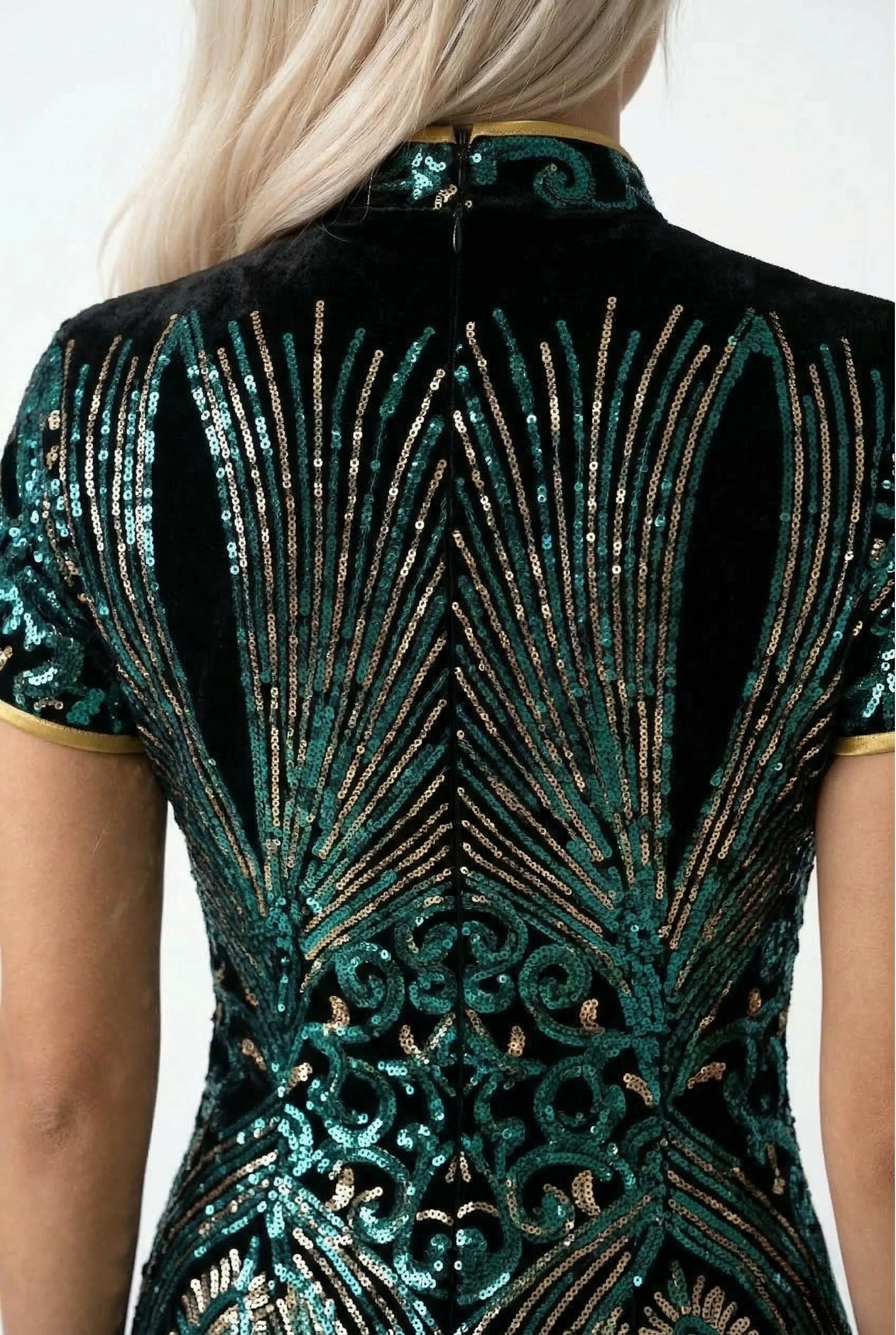 Close-up of the high side slit on a dark green midi Qipao dress paired with black pointed-toe heels.