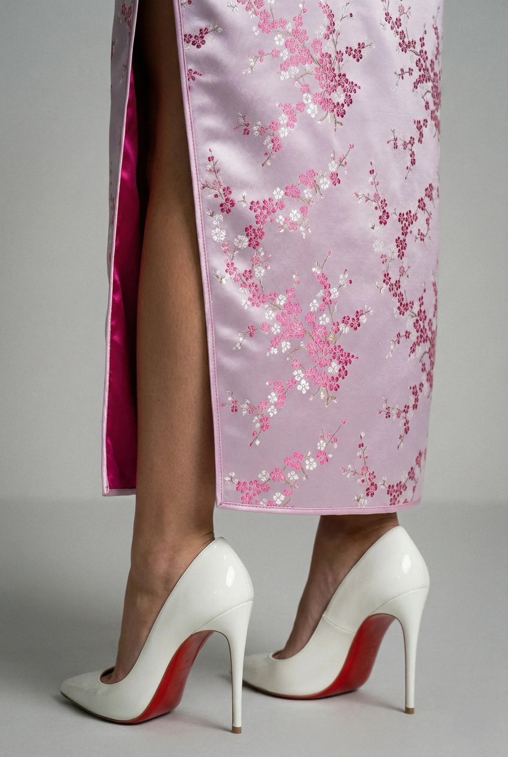 Side slit and floral silk fabric pattern close-up on a modern pink qipao