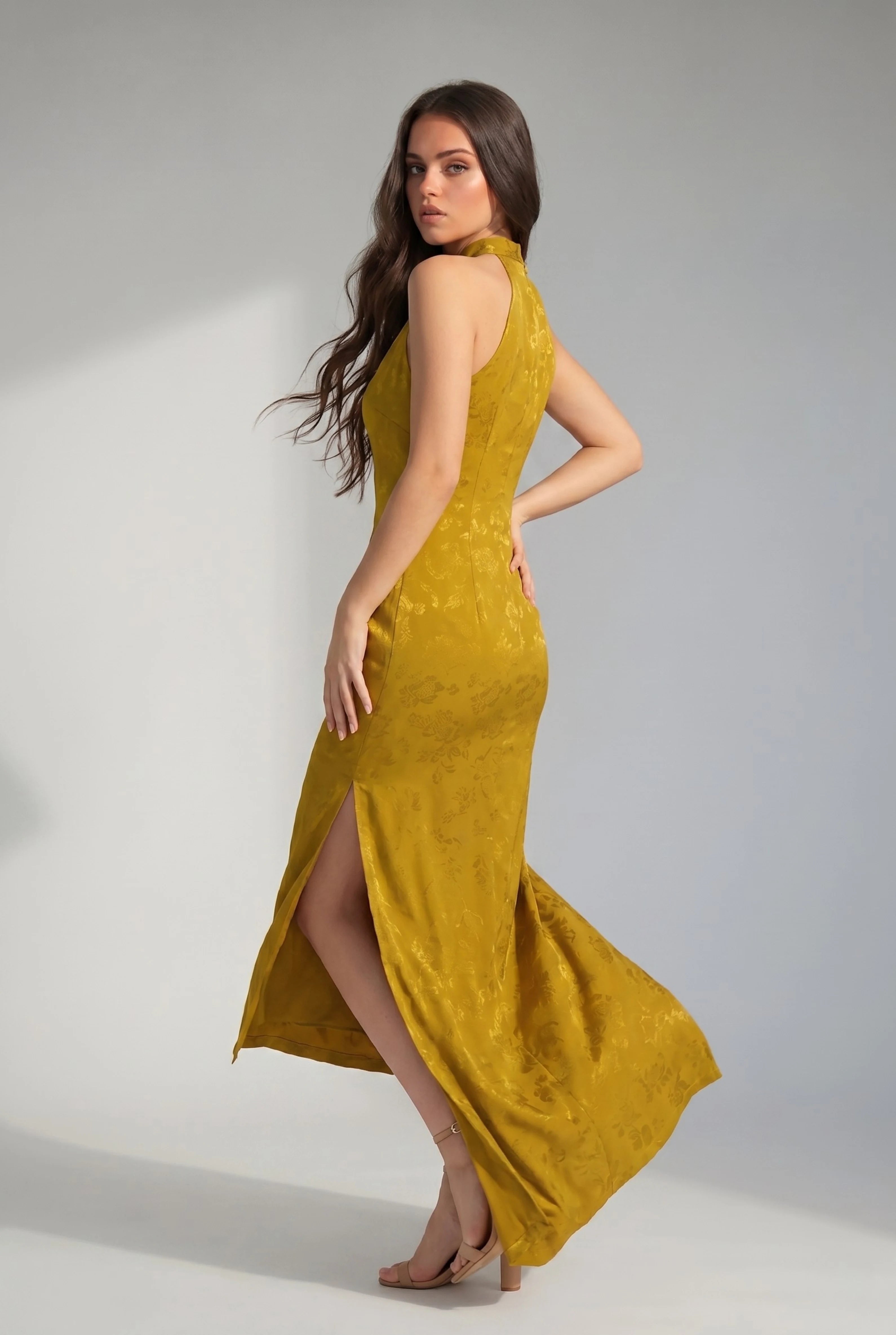 Side view of a woman turning in a mustard yellow Chinese dress, showing the movement and side slit
