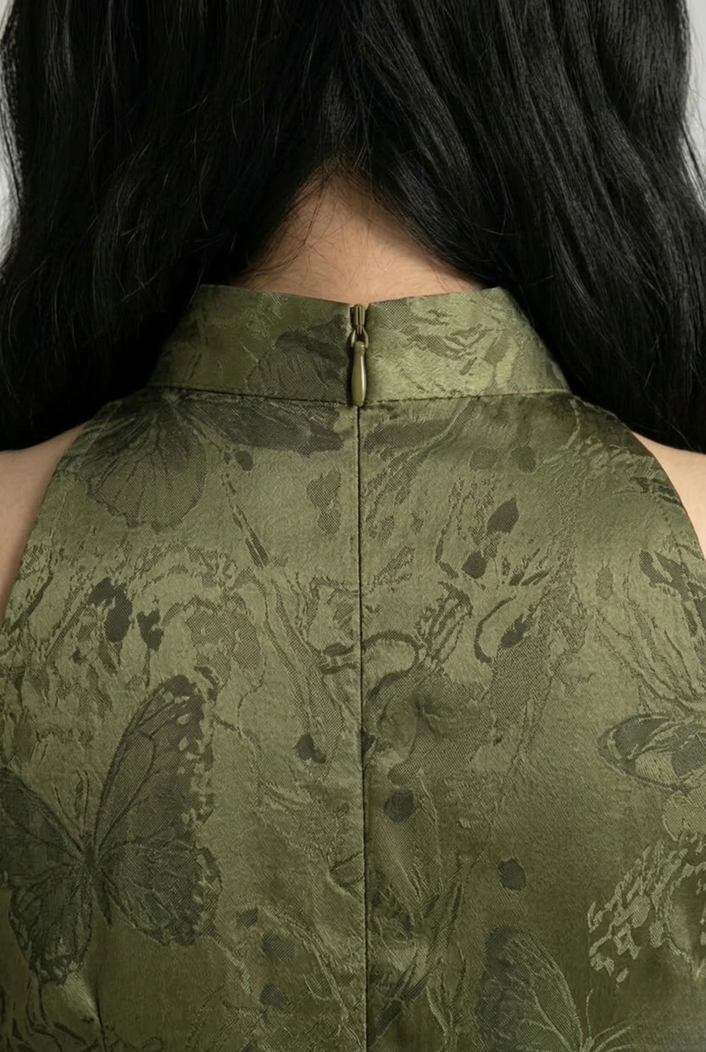 Detailed view of the high back collar and halter neckline of an olive green butterfly print Qipao.