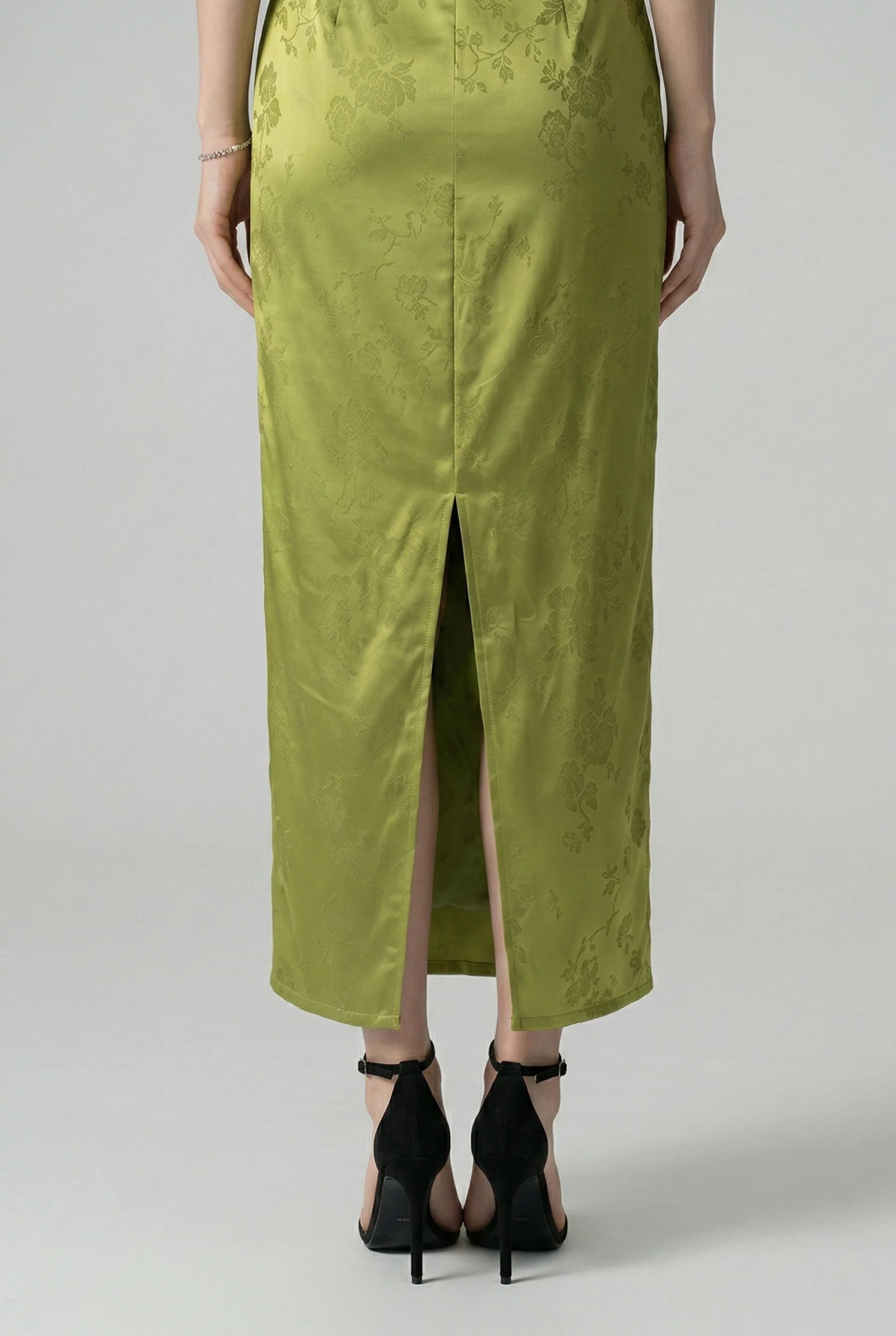 Close-up of the back hem slit and floral jacquard fabric on an olive qipao