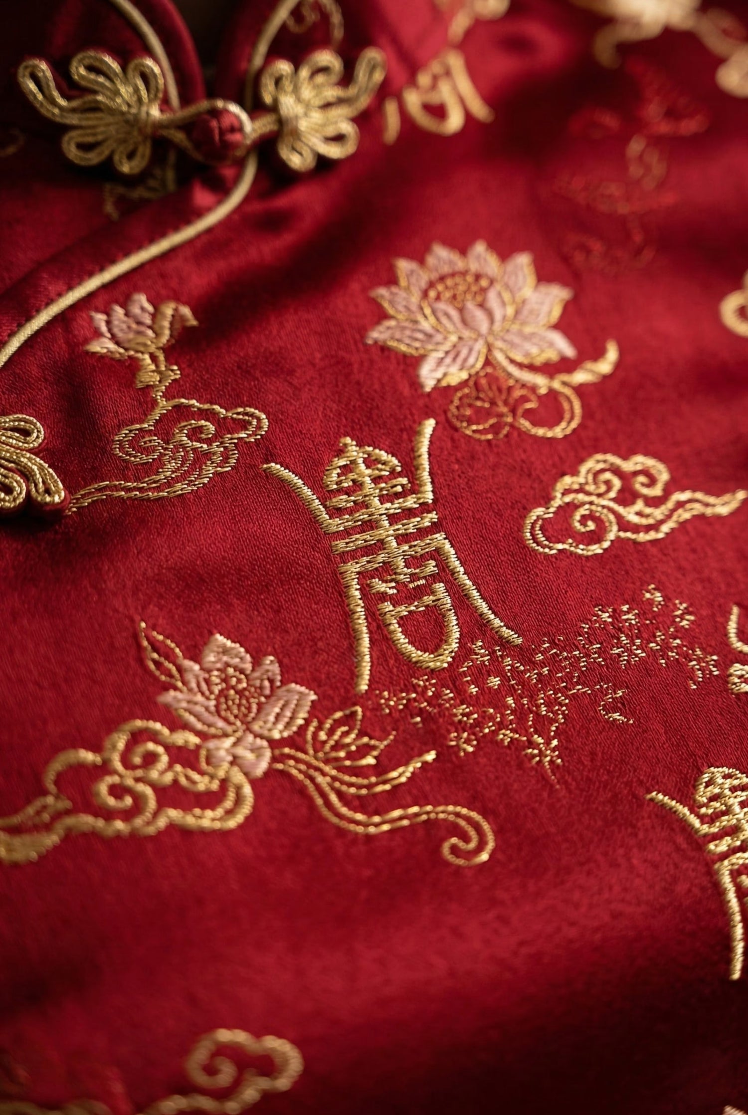 Close-up of gold embroidery and classical motifs on a traditional Chinese red dress, showing sophisticated silk texture