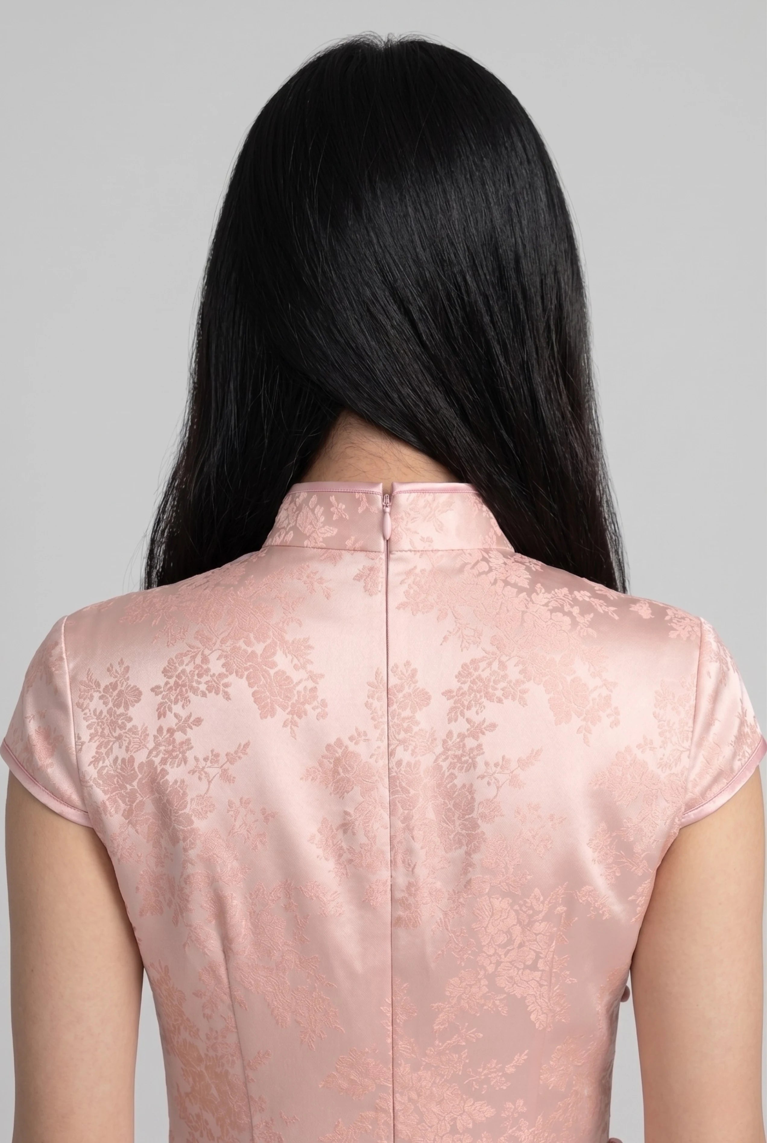Close-up back view showing the precise zipper closure and high collar structure of the pink cheongsam