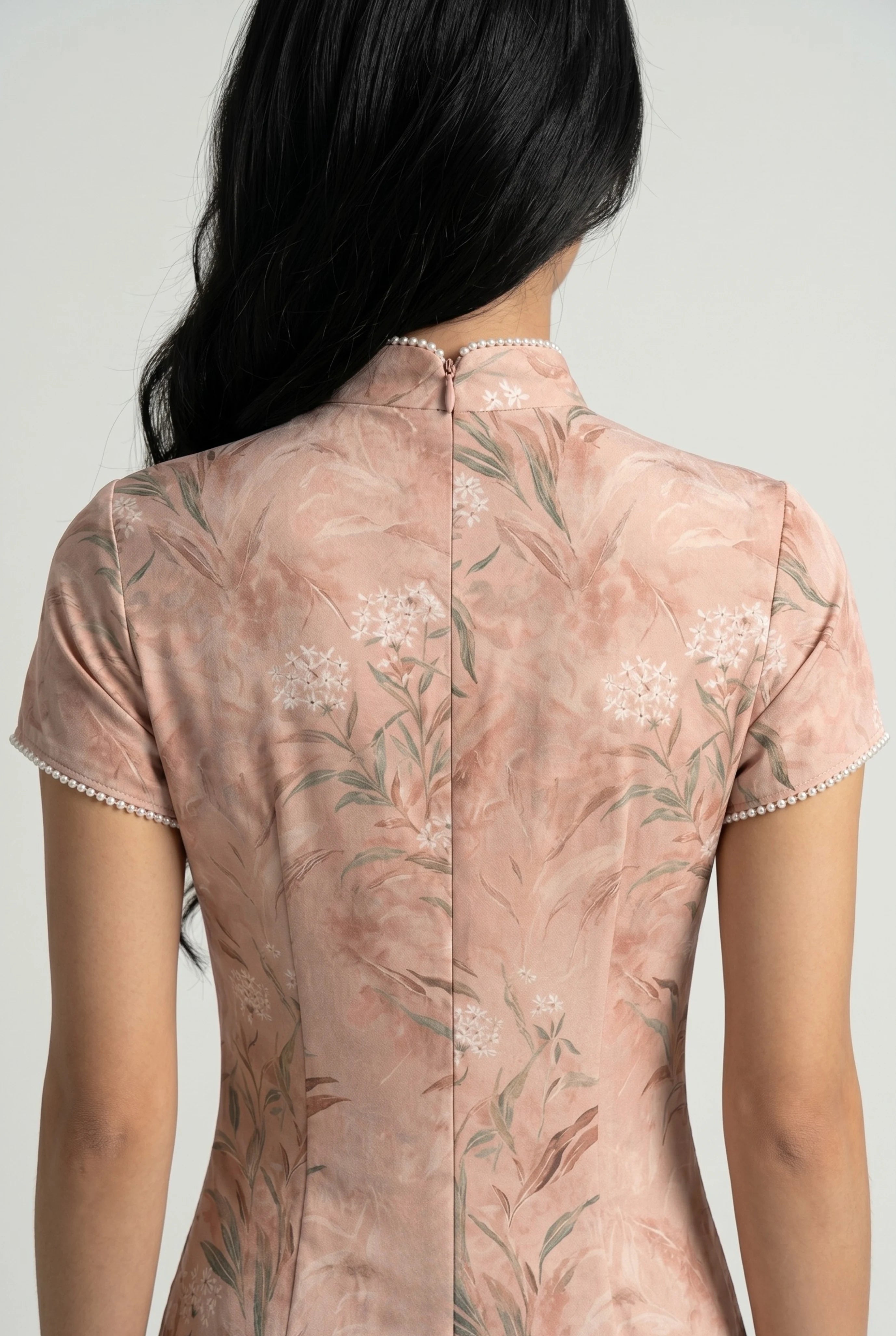 Close-up back view showing the hidden zipper closure, high collar structure, and seamless floral pattern on the pink cheongsam