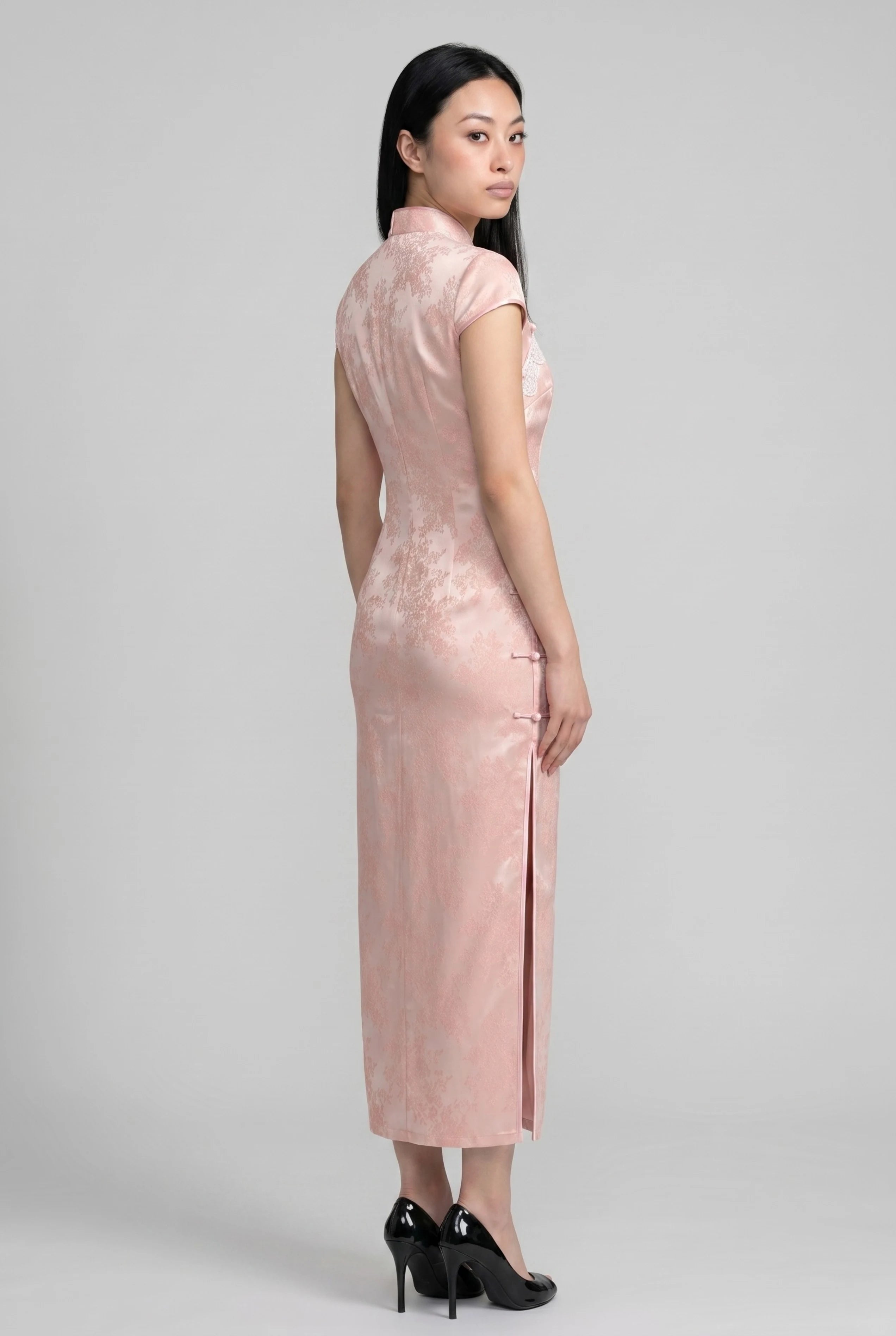 Three-quarter back profile view highlighting the tailored fit and subtle floral jacquard fabric of the pink qipao