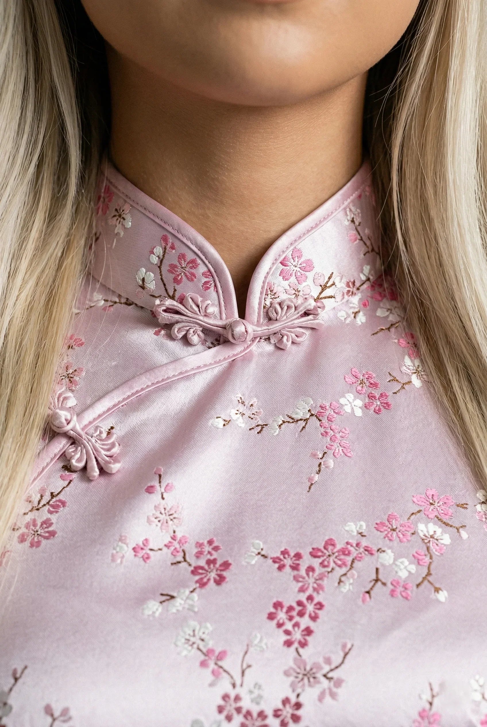 Detailed view of the patterned mandarin collar on a pink floral qipao
