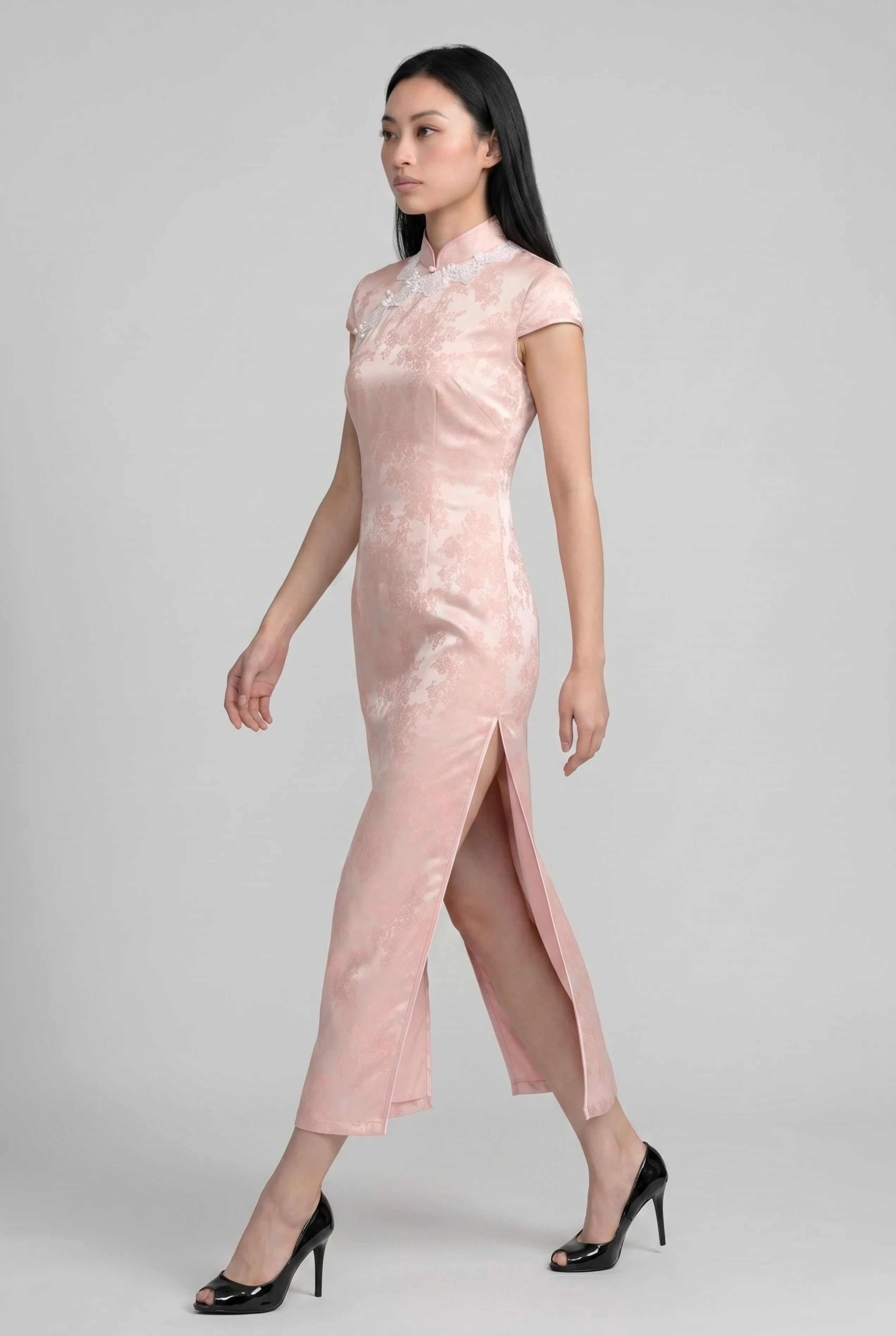Full-body side profile view of a woman in stride wearing the pink satin cheongsam dress paired with black heels